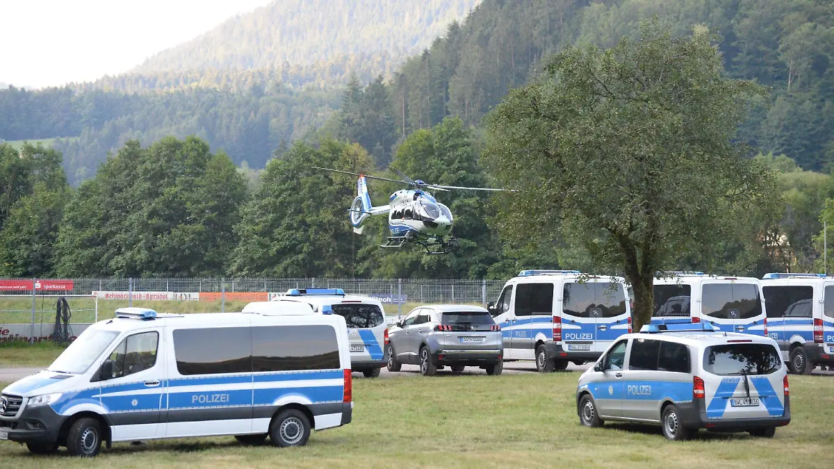 14.07.2020, Ortenaukreis, Oppenau: Ein Polizeihubschrauber startet von einem Sportplatz und überfliegt abgestellte Polizeifahrzeuge. Mit einem Großaufgebot setzt die Polizei die Suche nach einem 31-Jährigen fort, der vier Polizisten bedroht und ihnen ihre Dienstwaffen abgenommen hatte. Der Mann ohne festen Wohnsitz war nach der Tat am Sonntagmorgen in den Wald geflüchtet. Foto: Sdmg / Kohls/dpa +++ dpa-Bildfunk +++