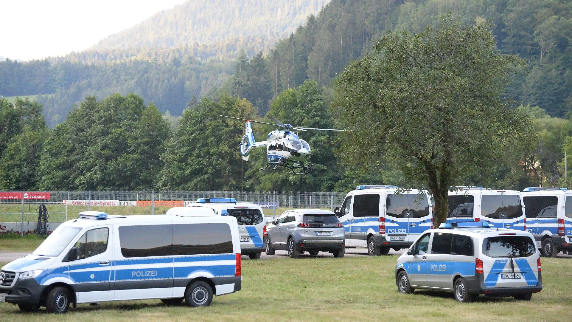 14.07.2020, Ortenaukreis, Oppenau: Ein Polizeihubschrauber startet von einem Sportplatz und überfliegt abgestellte Polizeifahrzeuge. Mit einem Großaufgebot setzt die Polizei die Suche nach einem 31-Jährigen fort, der vier Polizisten bedroht und ihnen ihre Dienstwaffen abgenommen hatte. Der Mann ohne festen Wohnsitz war nach der Tat am Sonntagmorgen in den Wald geflüchtet. Foto: Sdmg / Kohls/dpa +++ dpa-Bildfunk +++