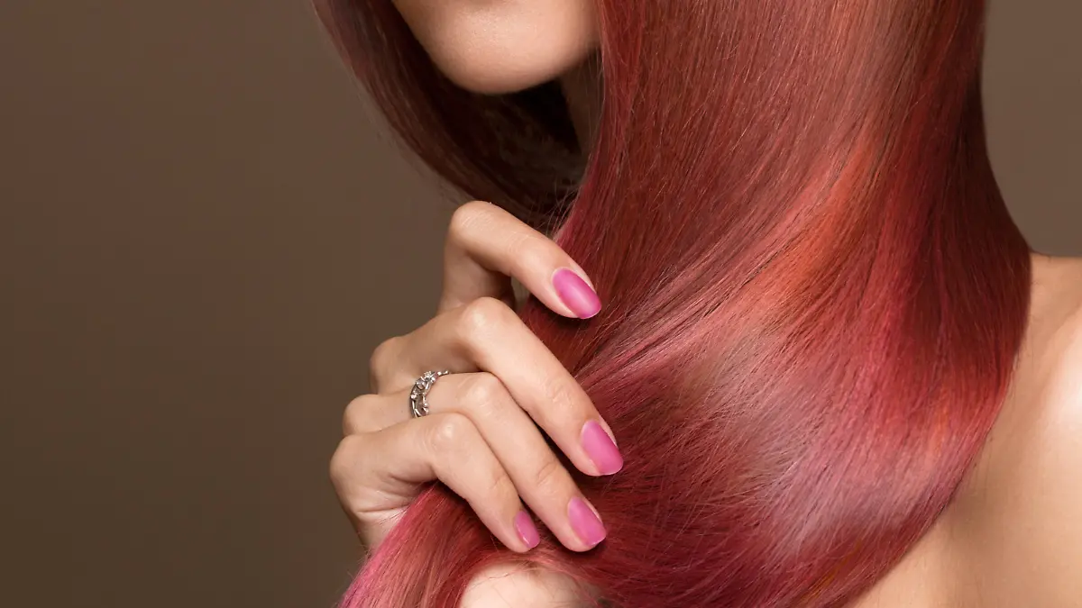 Beautiful pink-haired girl in move with a perfectly smooth hair, and classic make-up. Beauty face. Picture taken in the studio.