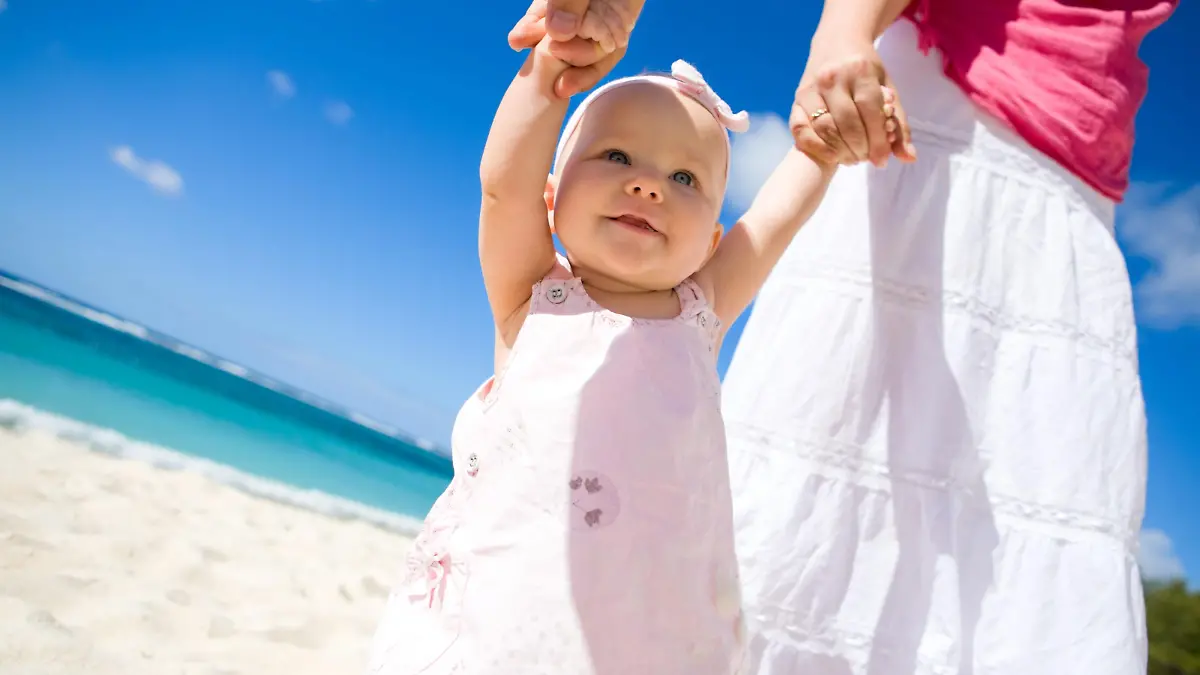 Young family with baby girl on white sand tropical beach