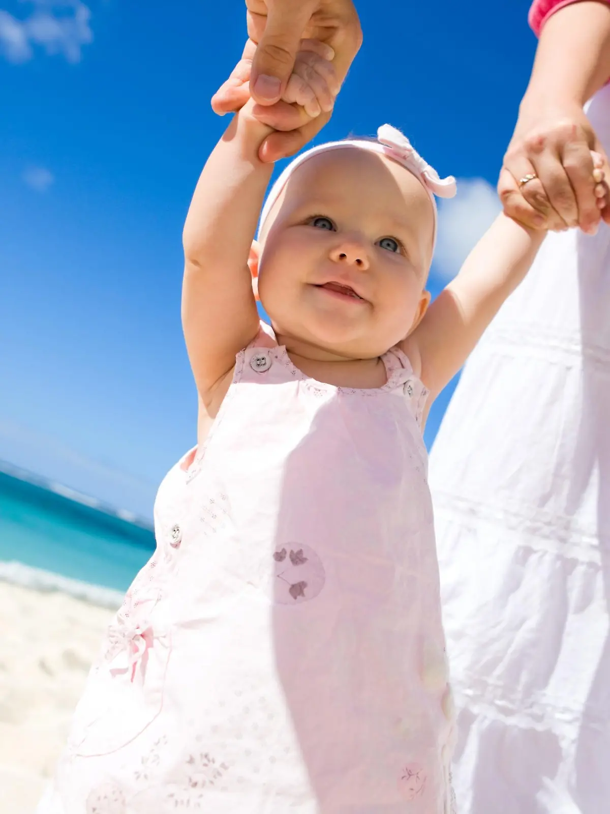 Young family with baby girl on white sand tropical beach