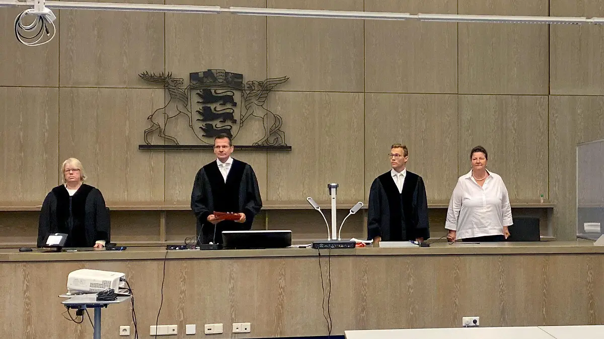 15.07.2020, Baden-Württemberg, Mannheim: Ein Angeklagter (2.v.r) steht vor Beginn der Urteilsverkündung mit einem Aktenordner vor dem Gesicht im Gerichtssaal zwischen seinen Anwälten Steffen Lindeberg (r) und Ute Mannebach-Junge (3.v.r). Der Vorsitzende Richter Gerd Rackwitz (2.v.l) verkündet das Urteil. Nach einem tödlichen Angriff mit einem Hammer und einem Messer auf seine Ex-Freundin ist der 34-Jährige wegen Mordes zu lebenslanger Haft verurteilt worden. (zu dpa «Ex-Partnerin mit Hammer und Messer getötet - lebenslange Haft») Foto: Julian Weber/dpa +++ dpa-Bildfunk +++