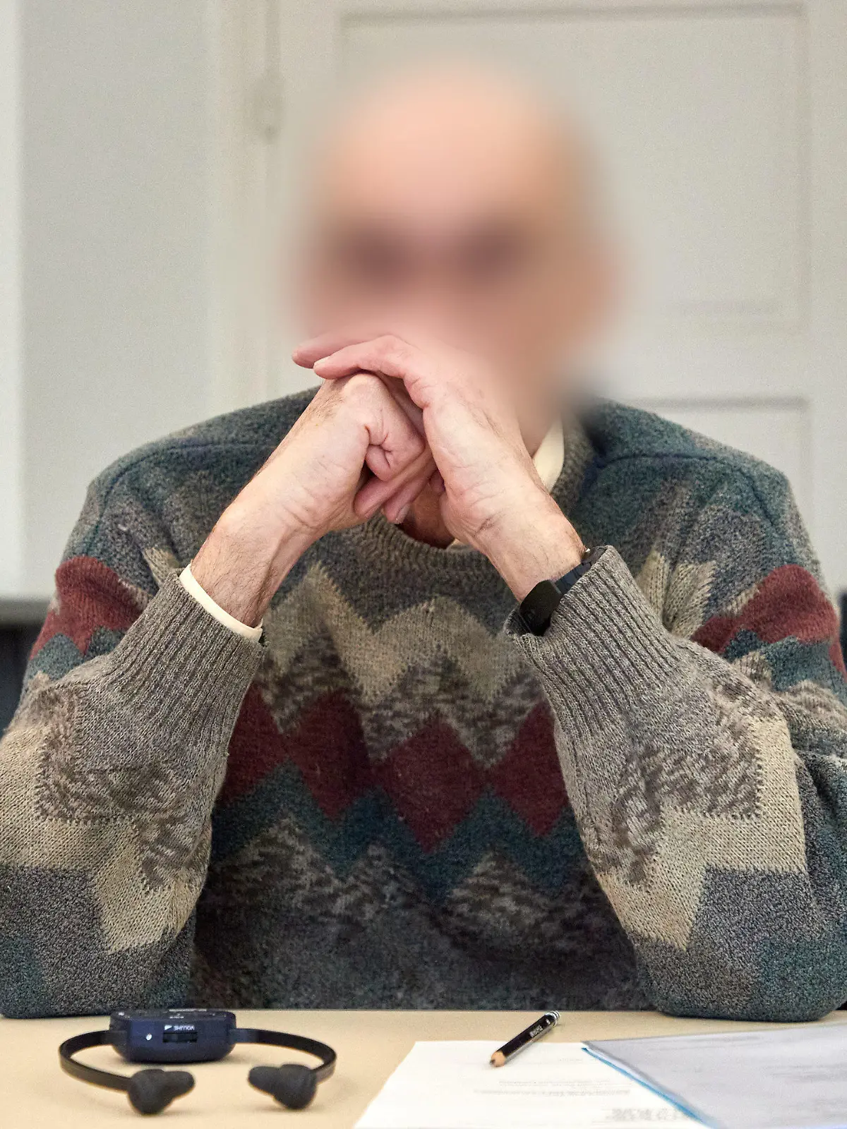 23.03.2023, Niedersachsen, Lüneburg: Der Angeklagte sitzt im Landgericht Lüneburg vor Beginn des Prozesses im Gerichtssaal. Dem Angeklagten wird besonders schwerer sexueller Missbrauch vorgeworfen. Der inzwischen 74 Jahre alte Mann soll als Schwimmtrainer und Betreuer von Ferienfreizeiten in 84 Fällen Kinder zwischen acht und 13 Jahren missbraucht haben. Foto: Georg Wendt/dpa - ACHTUNG: Person(en) wurde(n) aus rechtlichen Gründen gepixelt +++ dpa-Bildfunk +++