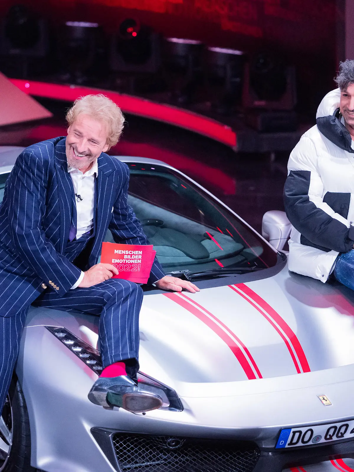 Thomas Gottschalk (l), Moderator, und Lotto-Millionär Kürsat Yildirim alias "Chico" sitzen auf einem Ferrari beim RTL-Jahresrückblick "Menschen, Bilder, Emotionen 2022" im Studio.