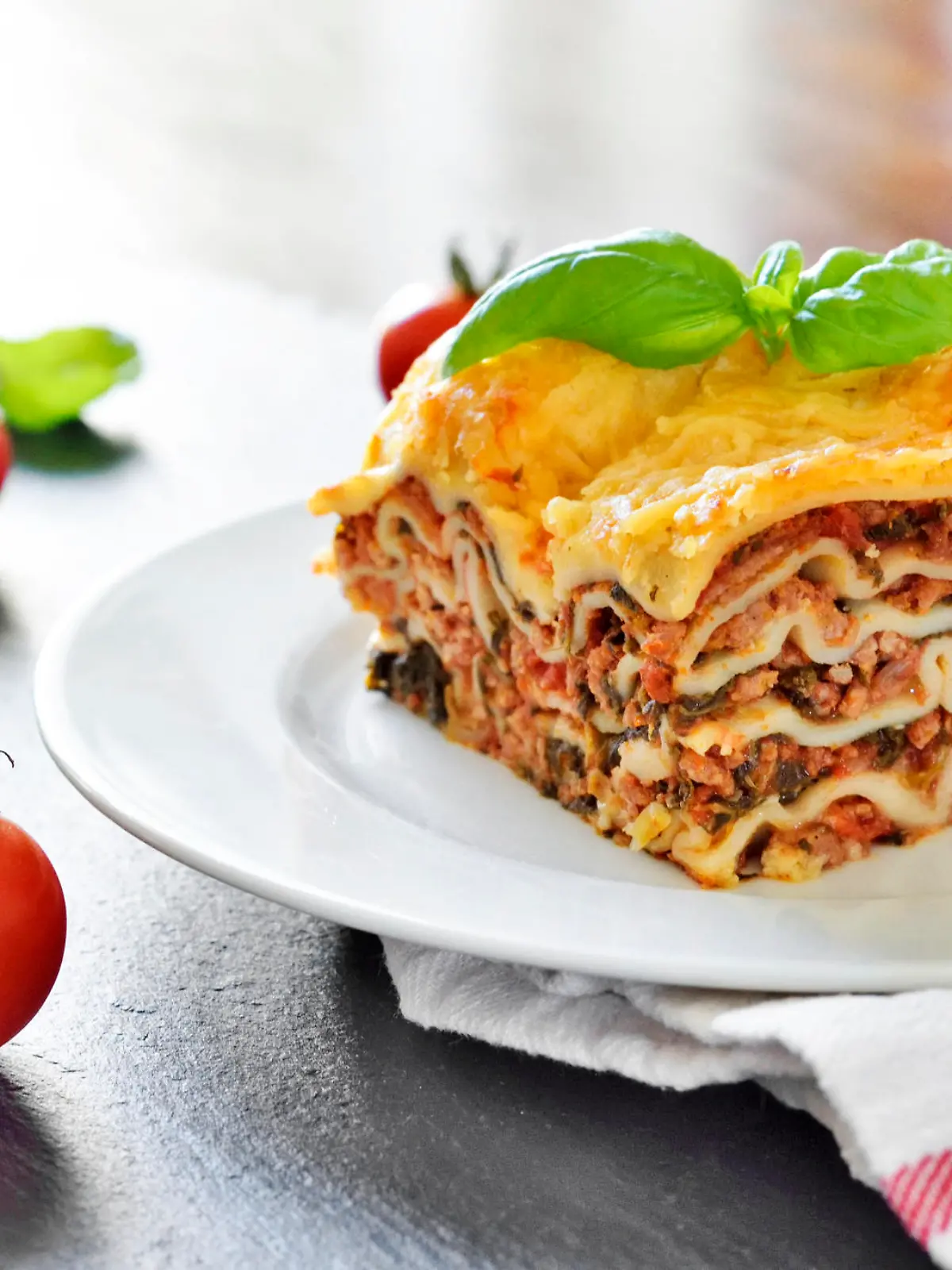 Fresh italian meat lasagne with cherry tomatoes. Italian pasta dish on a white plate.