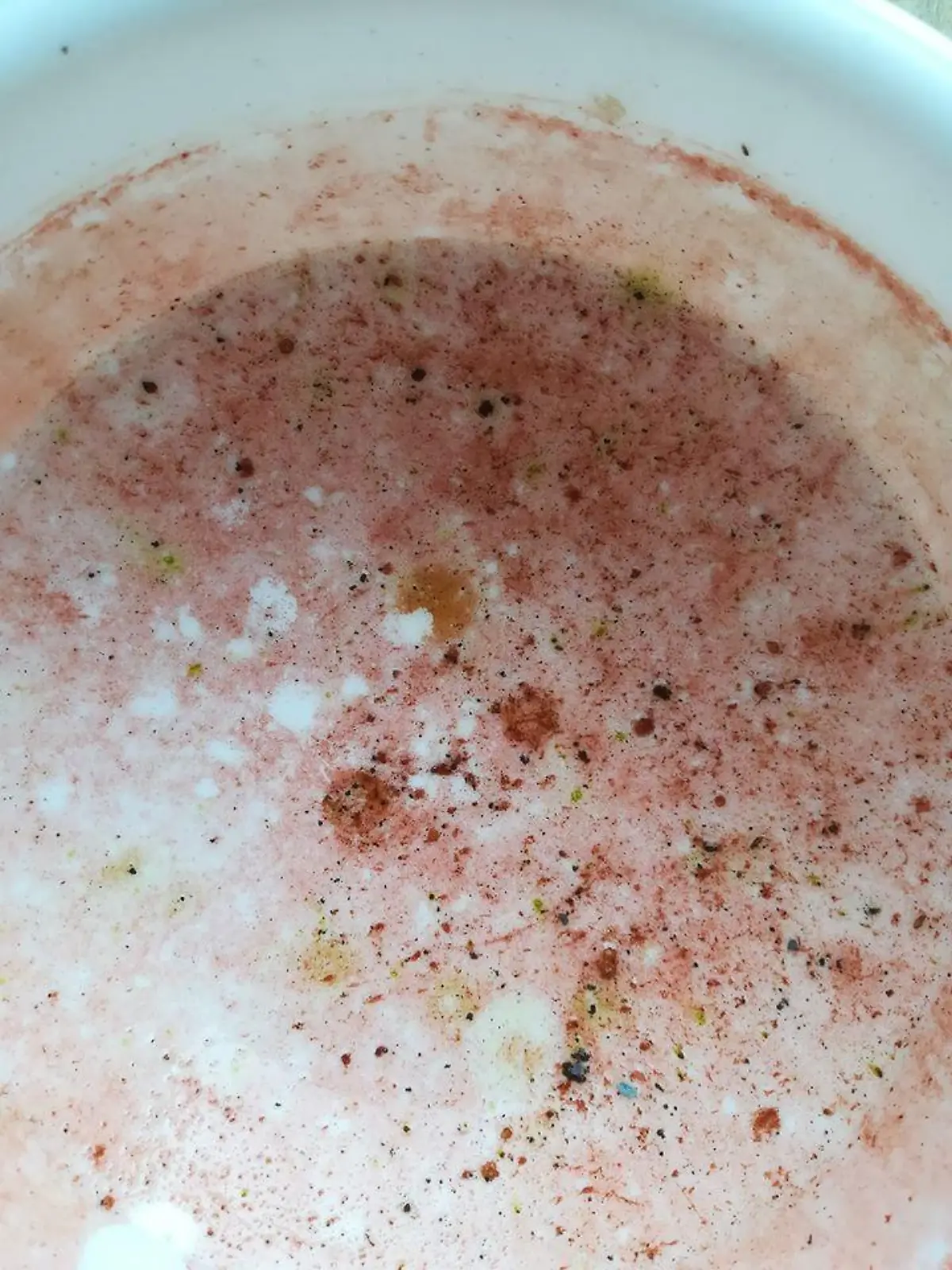 In einer Trinkschale für Vögel hat sich ein roter Belag gebildet.