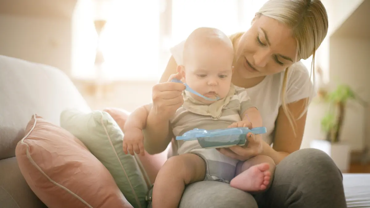 Mutter füttert Baby mit Beikost.