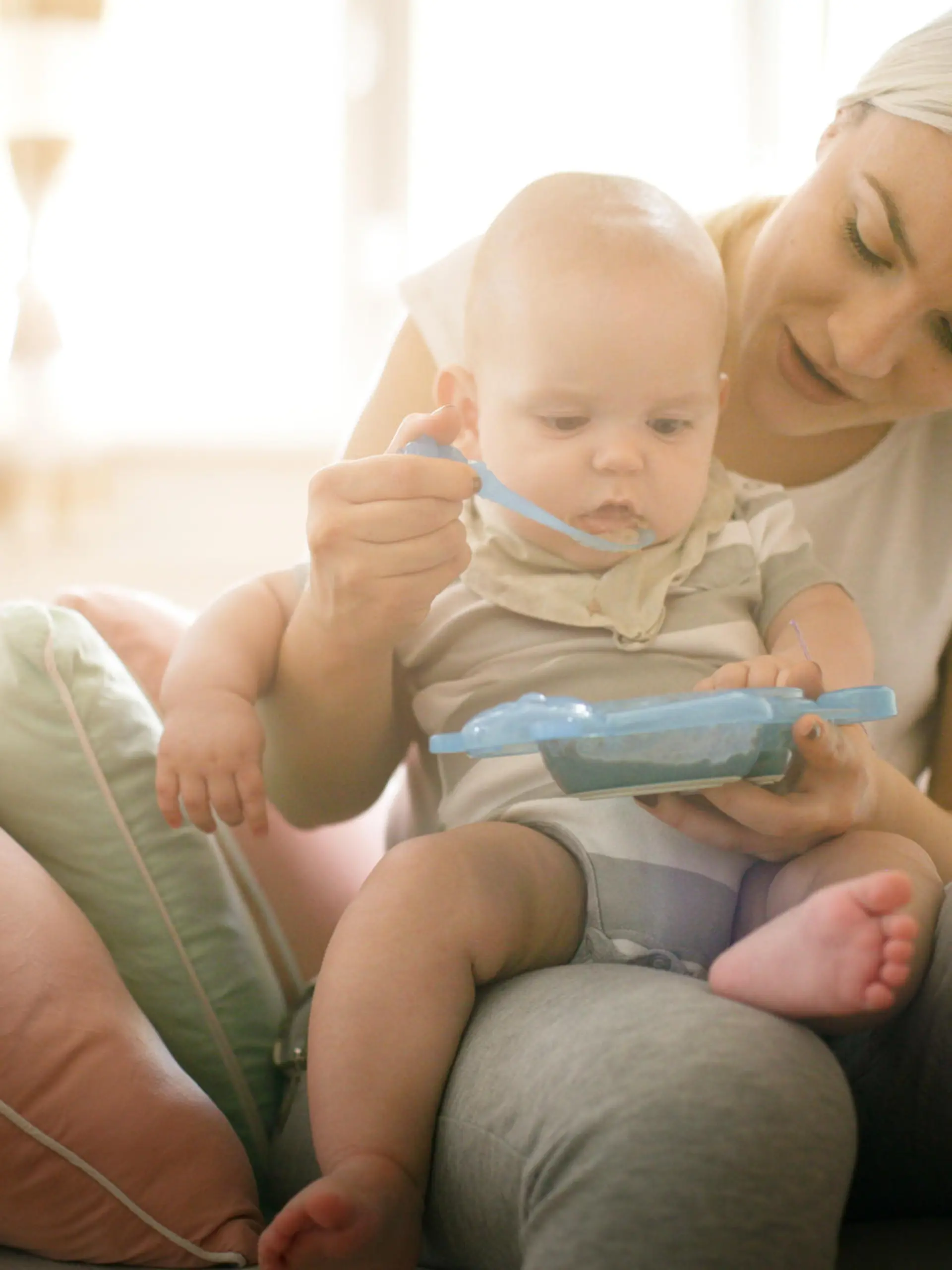 Mutter füttert Baby mit Beikost.