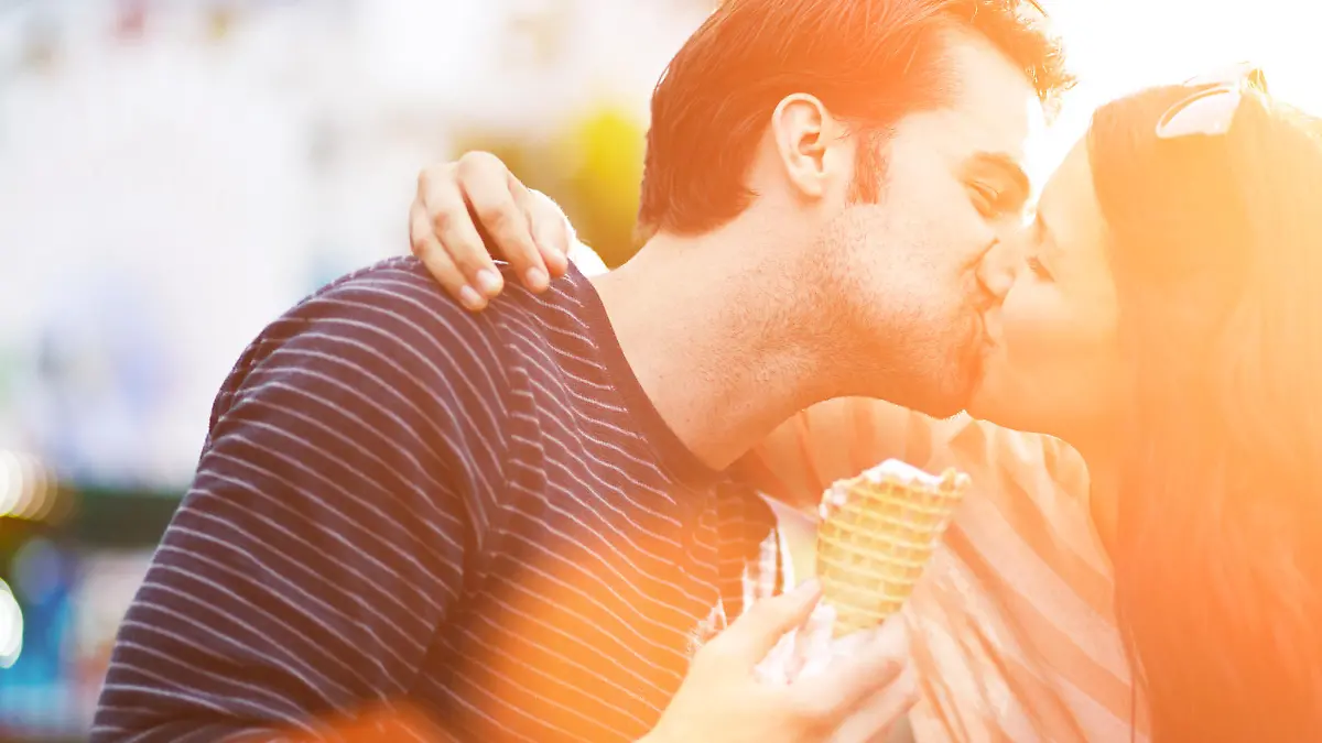 photo of a romantic couple kissing while holding ice cream