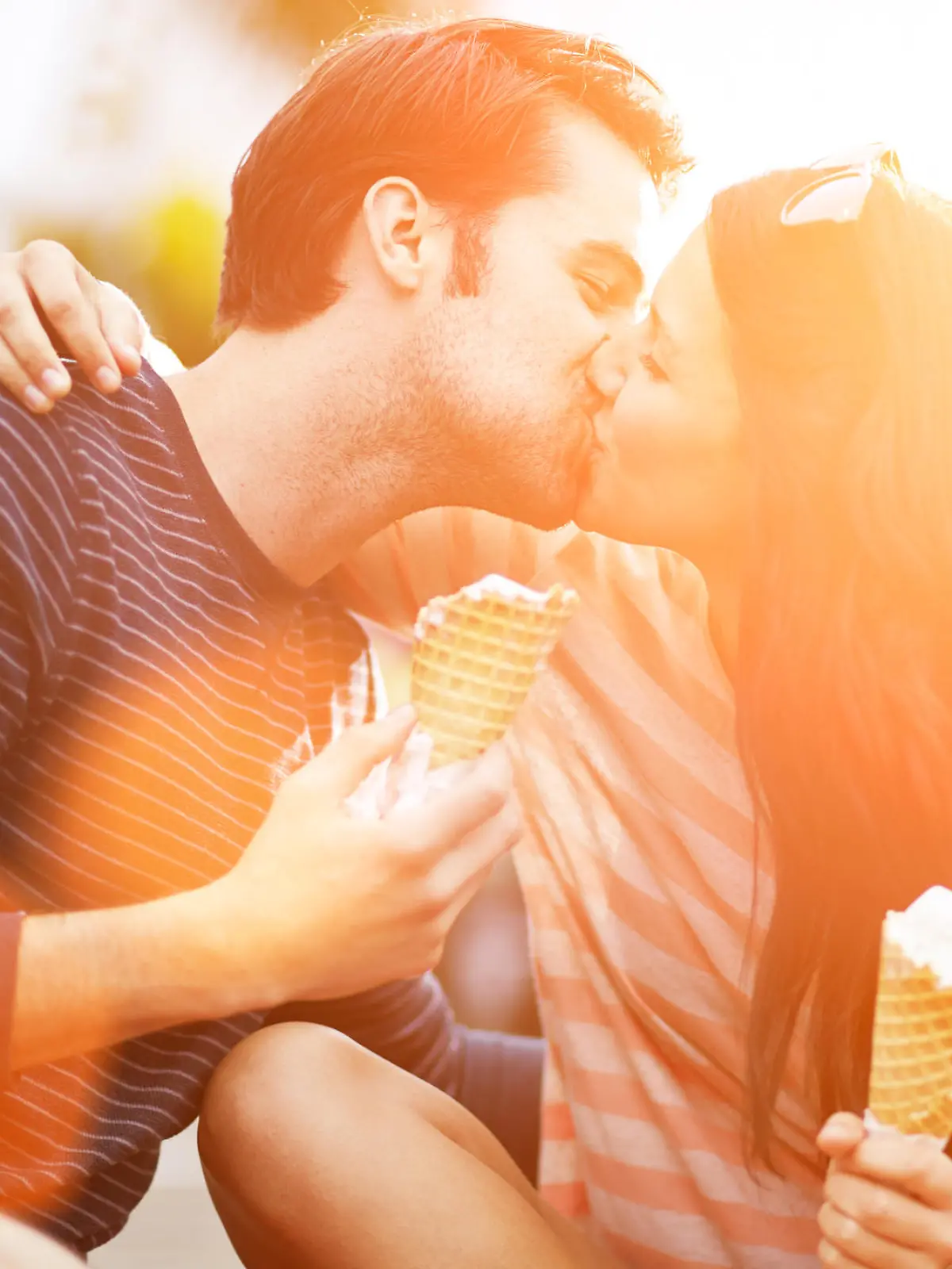 photo of a romantic couple kissing while holding ice cream