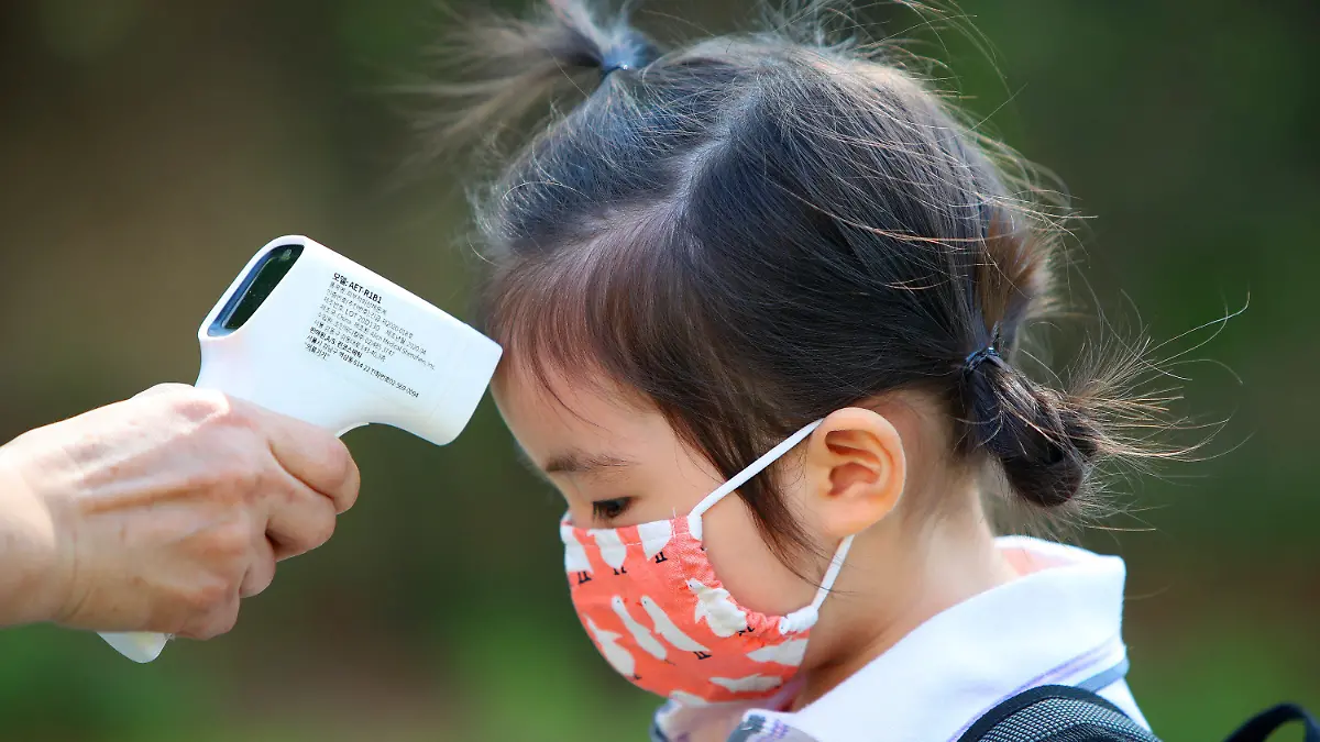 22.06.2020, Südkorea, Daegu: Einem Mädchen wird am ersten Tag der Wiedereröffnung einer Kindertagesstätte die Temperatur gemessen, nachdem die Kindertagesstätten der Region aufgrund der Corona-Pandemie 122 Tage geschlossen waren. Foto: -/YNA/dpa +++ dpa-Bildfunk +++