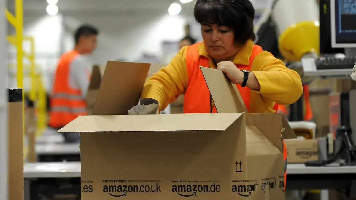 Ein Mitarbeiterin der Versandabteilung des Amazon Logistikzentrums in Pforzheim (Baden-Württemberg) legt am 11.12.2012 Waren in ein Paket. Das Weihnachtsgeschäft von Amazon läuft auf Hochtouren, auch das neue Logistikzentrum in Pforzheim mischt kräftig mit. Foto: Jan-Philipp Strobel/dpa  +++(c) dpa - Bildfunk+++