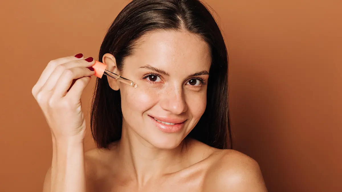 Frau trägt Serum aufs Gesicht auf.