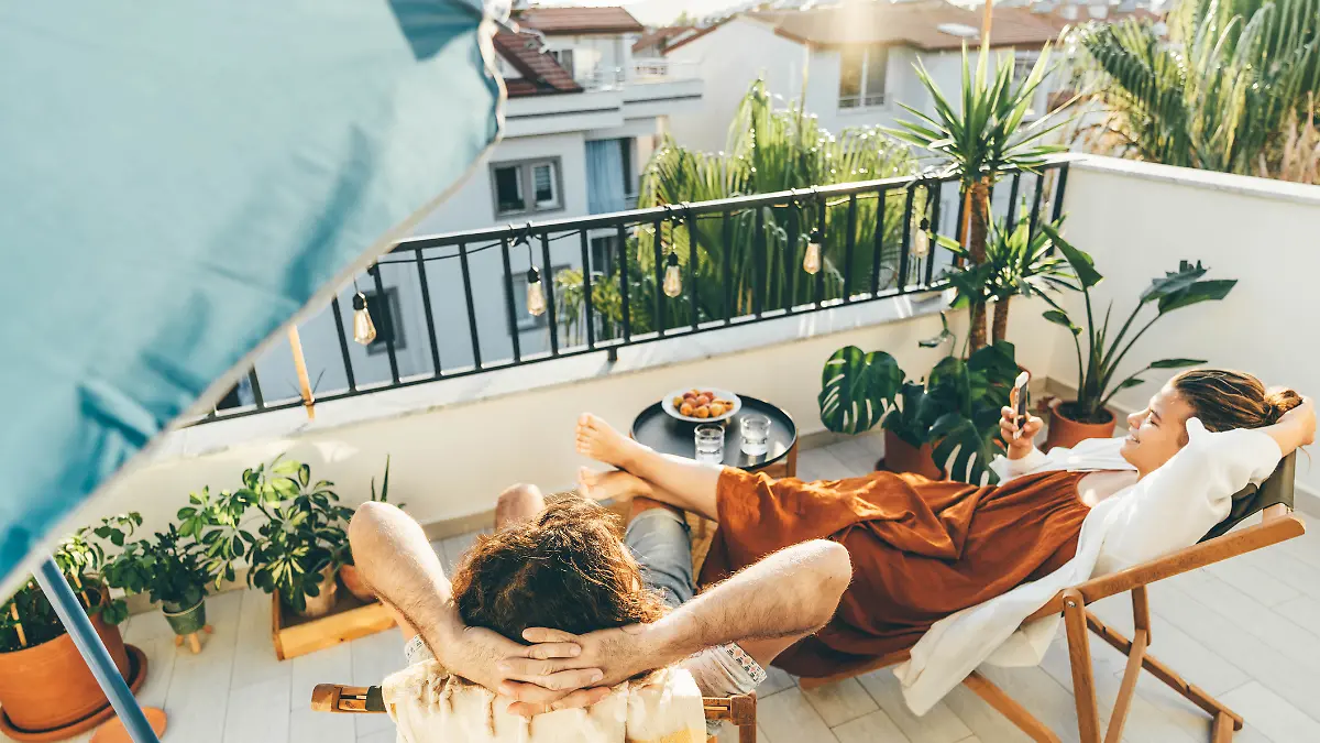 Ein Pärchen sitzt auf dem Balkon und genießt die Sonne. 