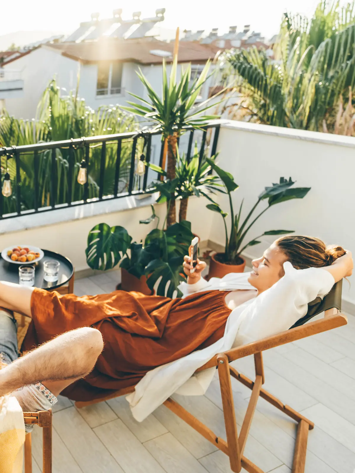 Ein Pärchen sitzt auf dem Balkon und genießt die Sonne. 