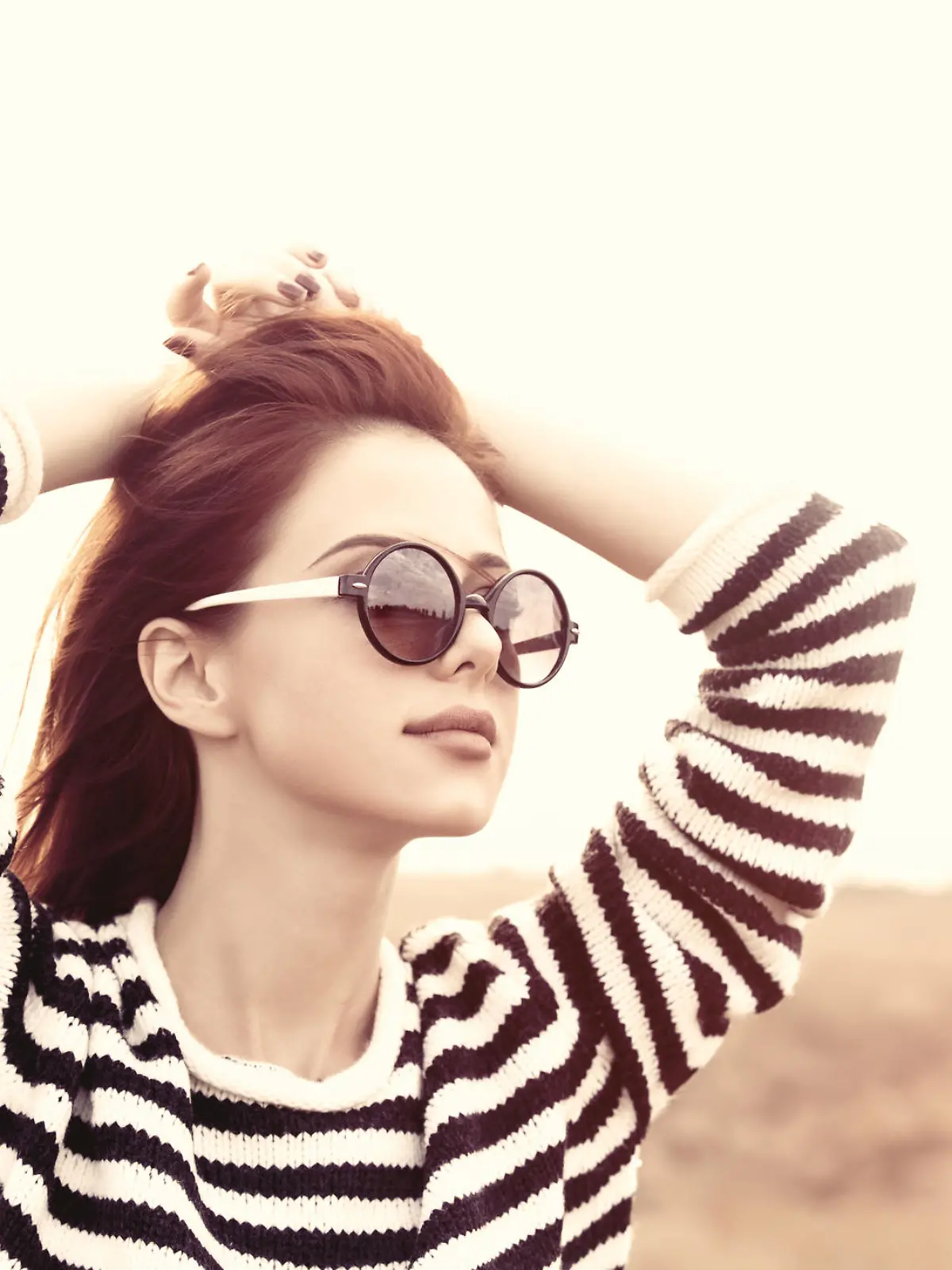 Portrait of a young redhead girl in sunglasses and striped sweater at outdoor in autumn time