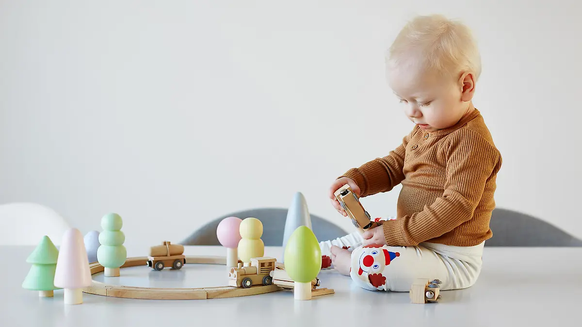 Baby spielt mit Holzeisenbahn