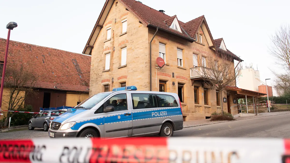 ARCHIV - 24.01.2020, Baden-Württemberg, Rot am See: Nach Schüssen in Rot am See im Nordosten Baden-Württembergs steht ein Polizeiauto hinter einer Absperrung an einem Haus. Hier sind mehrere Menschen getötet worden. (zu dpa: «Prozess um Bluttat in Rot am See startet») Foto: Tom Weller/dpa +++ dpa-Bildfunk +++
