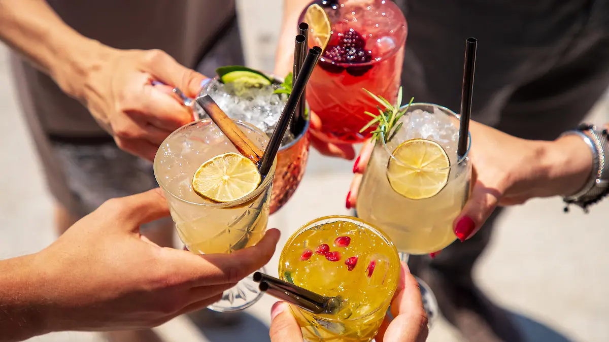 Five exotic cocktails on ice in hands joined in celebratory toast