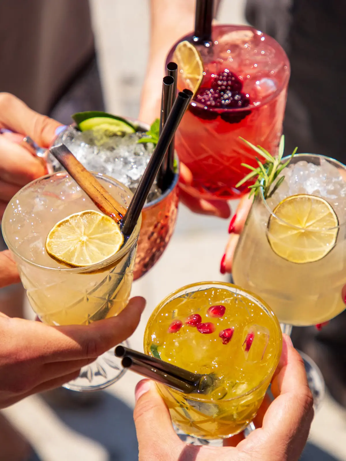 Five exotic cocktails on ice in hands joined in celebratory toast