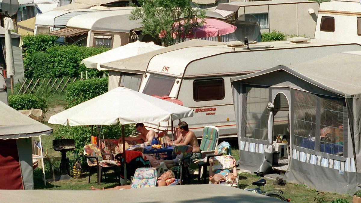 ARCHIV - 08.05.2000, Berlin, Eichhorst: Dicht gedrängt genießen Camper an einem See die Sommersonne. Die Welt entdecken ohne auf Fahrpläne oder Hotels angewiesen zu sein, das fasziniert viele Menschen. Ein Zuhause auf Rädern bietet Mobilität und Bequemlichkeit zugleich. (zu dpa "Unterwegs zuhause - Notizen aus der Geschichte des mobilen Wohnens") Foto: Klaus Franke/dpa-Zentralbild/dpa +++ dpa-Bildfunk +++