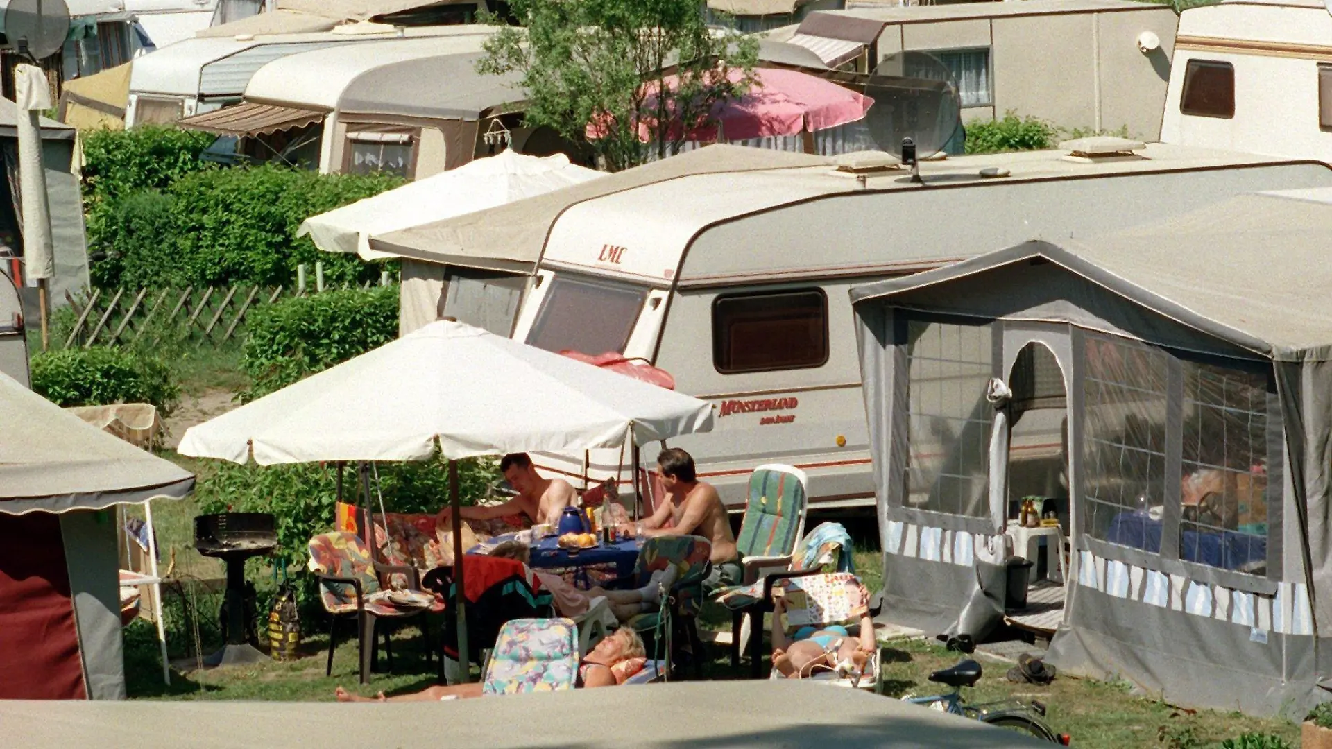 ARCHIV - 08.05.2000, Berlin, Eichhorst: Dicht gedrängt genießen Camper an einem See die Sommersonne. Die Welt entdecken ohne auf Fahrpläne oder Hotels angewiesen zu sein, das fasziniert viele Menschen. Ein Zuhause auf Rädern bietet Mobilität und Bequemlichkeit zugleich. (zu dpa "Unterwegs zuhause - Notizen aus der Geschichte des mobilen Wohnens") Foto: Klaus Franke/dpa-Zentralbild/dpa +++ dpa-Bildfunk +++
