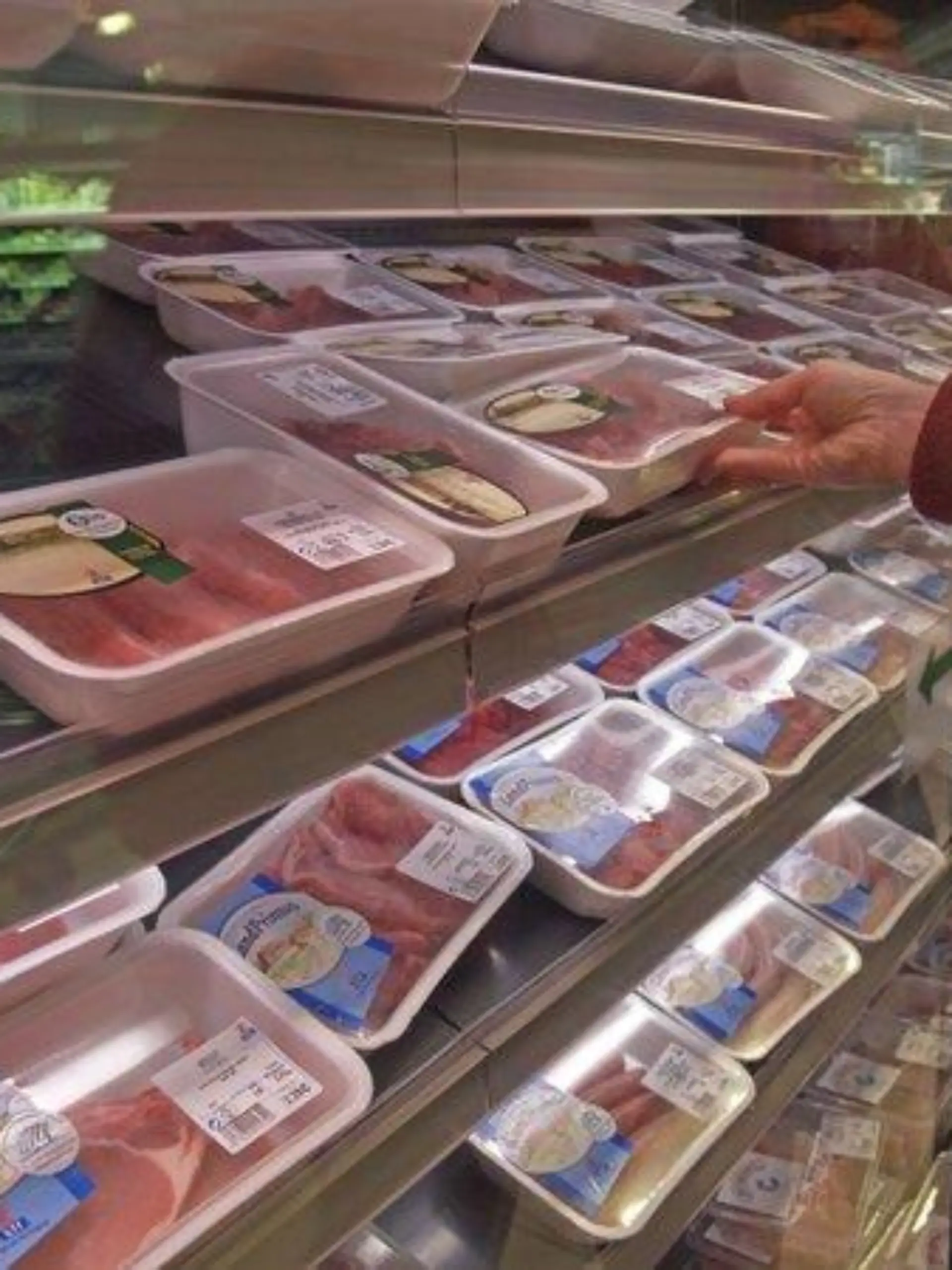 MR Verbraucher Person beim Einkaufen im Supermarkt vor Regal Kühlregal mit abgepacktem Fleisch Hand greift eine Packung / MR person consumer going shopping in supermarket in front of cold shelves with prepacked prepackaged meat hand reaching for one package meat Keine Weitergabe an Drittverwerter.