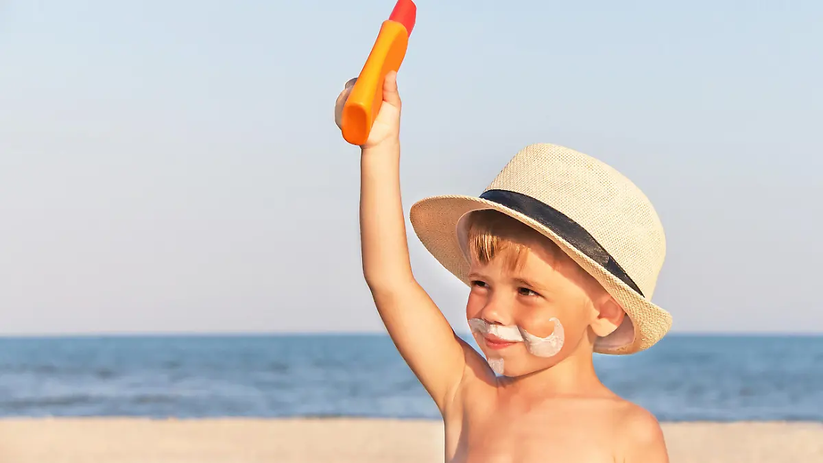 Kleiner Junge mit Sonnenmilch im Gesicht.