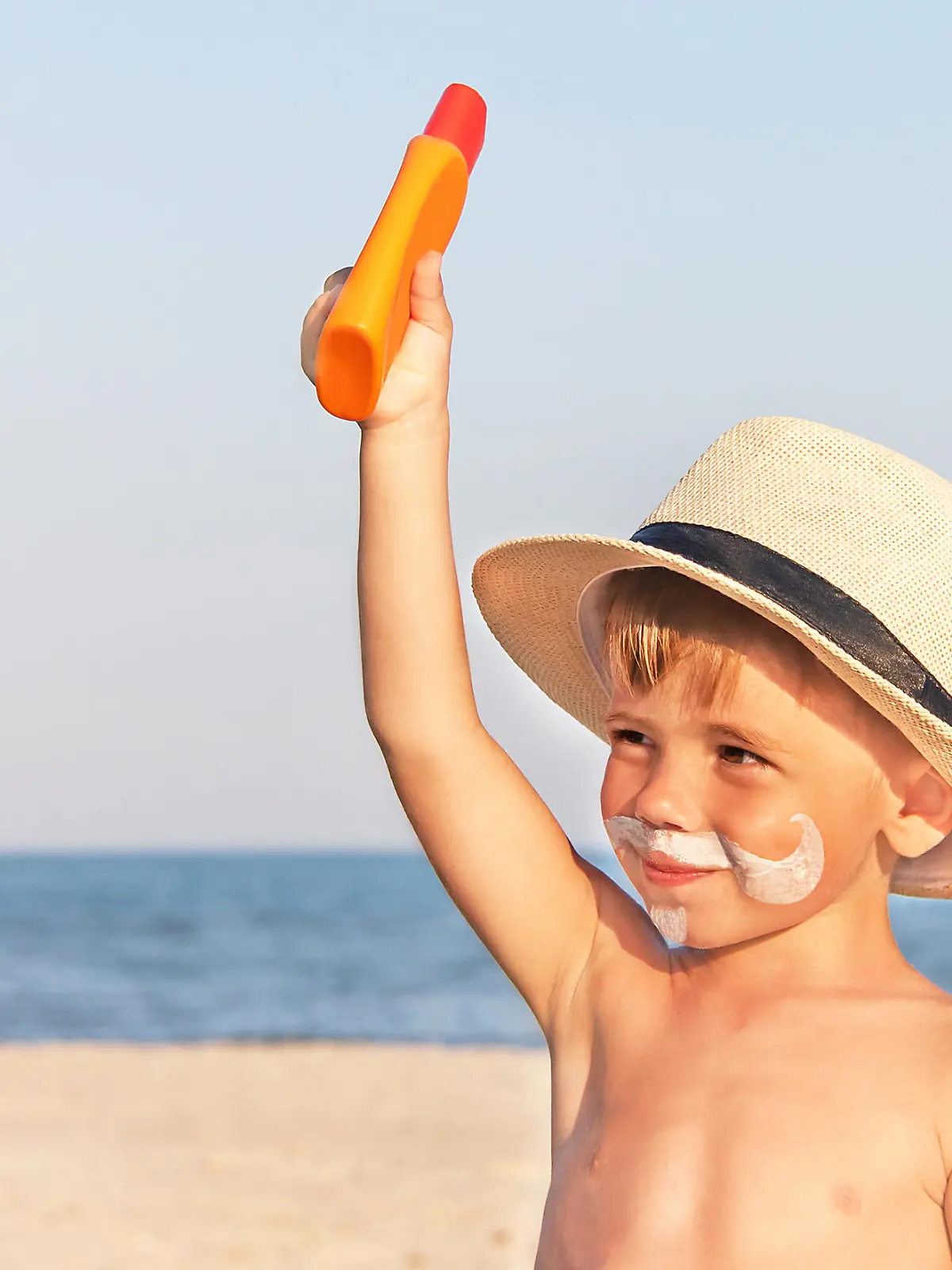 Kleiner Junge mit Sonnenmilch im Gesicht.