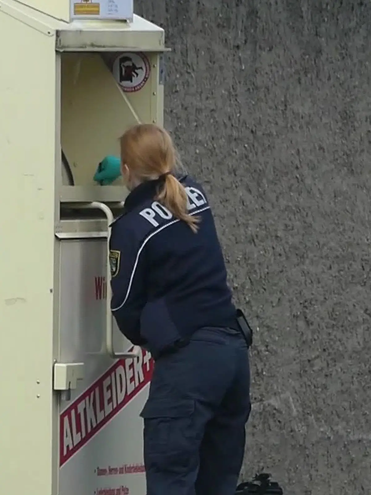 Eine Polizistin nimmt beim Altkleidercontainer Spuren