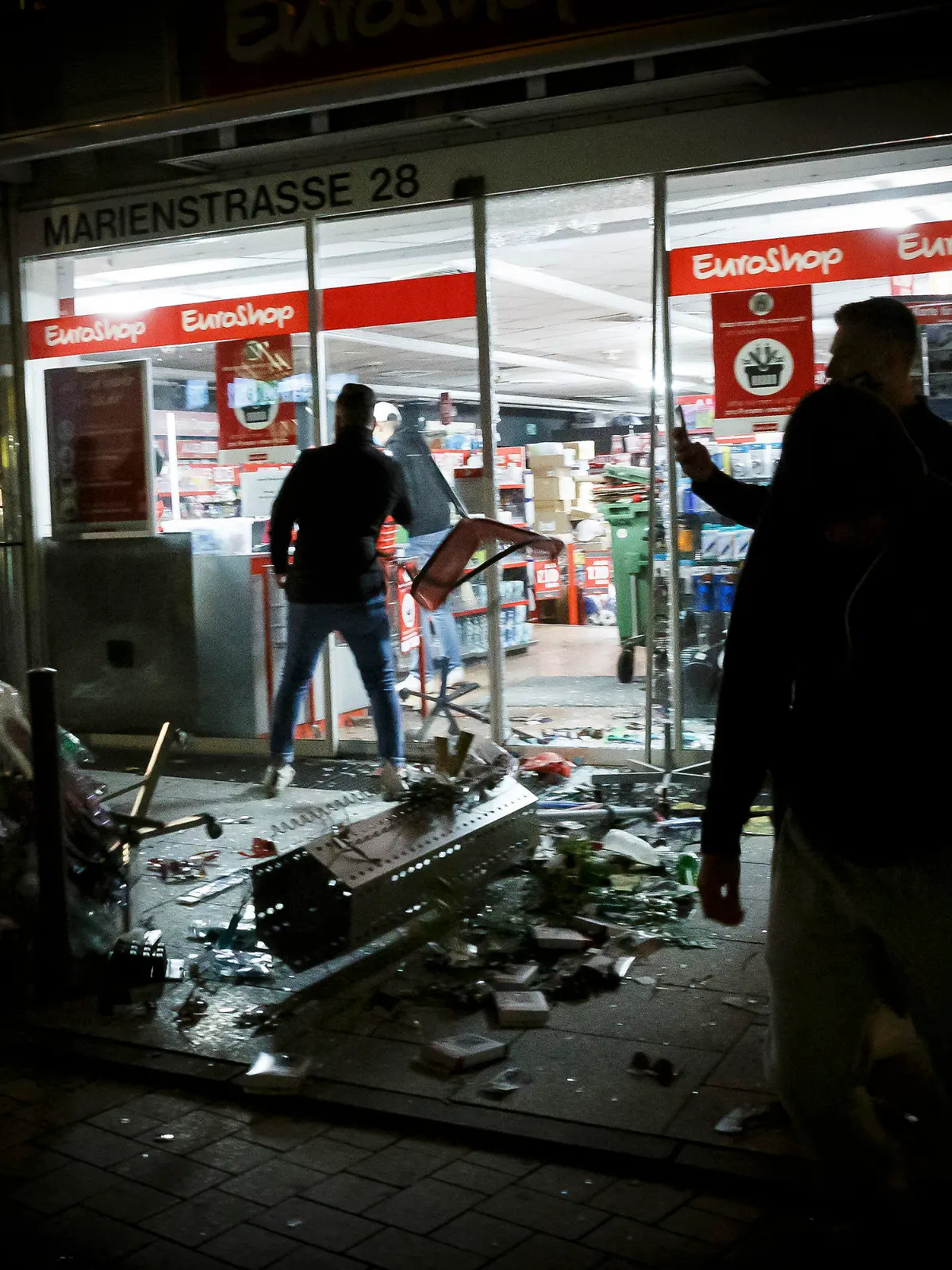 21.06.2020, Baden-Württemberg, Stuttgart: Menschen stehen vor einem geplünderten Geschäft in der Marienstraße. Bei Auseinandersetzungen mit der Polizei haben dutzende gewalttätige Kleingruppen die Innenstadt verwüstet und mehrere Beamte verletzt. Foto: Julian Rettig/dpa +++ dpa-Bildfunk +++