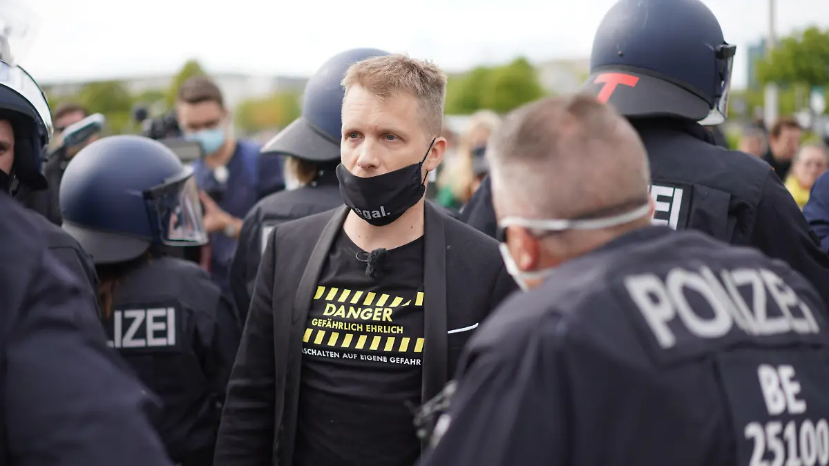 16.05.2020, Berlin: Comedian Oliver Pocher (M) im Gespräch mit einem Polizisten vor dem Reichstag. Vor dem Reichstagsgebäude hatten sich mehrere Hundert Menschen versammelt, um an einer Kundgebung des bekannten Kochs Hildmann teilzunehmen. Pocher, der mit Hildmann vor laufenden Kameras diskutiert hatte, wurde von der Polizei vom Gelände geleitet. Foto: Jörg Carstensen/dpa +++ dpa-Bildfunk +++
