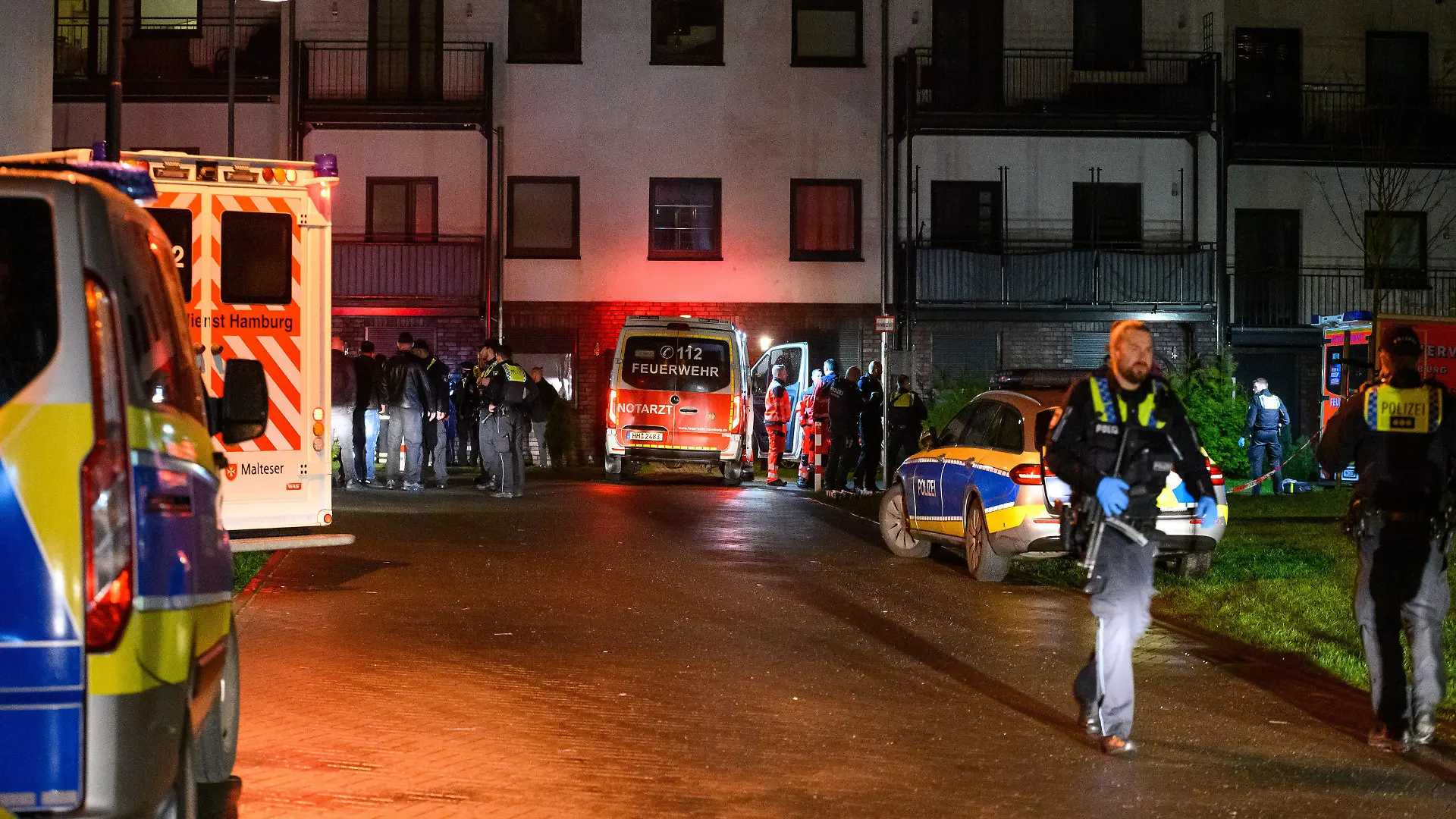 26.03.2023, Hamburg: Polizisten, Ermittler und Rettungskräfte stehen am abgesperrten Tatort. Zwei Männer sind am späten Samstagabend in Hamburg-Langenhorn durch Schüsse ums Leben gekommen. Laut Angaben der Staatsanwaltschaft Hamburg von Sonntag handelt es sich bei einem der Toten um den mutmaßlichen Schützen. Der Mann soll nach dem derzeitigen Stand der Ermittlungen den anderen Mann mit mehreren Schüssen getötet haben. Foto: Jonas Walzberg/dpa +++ dpa-Bildfunk +++