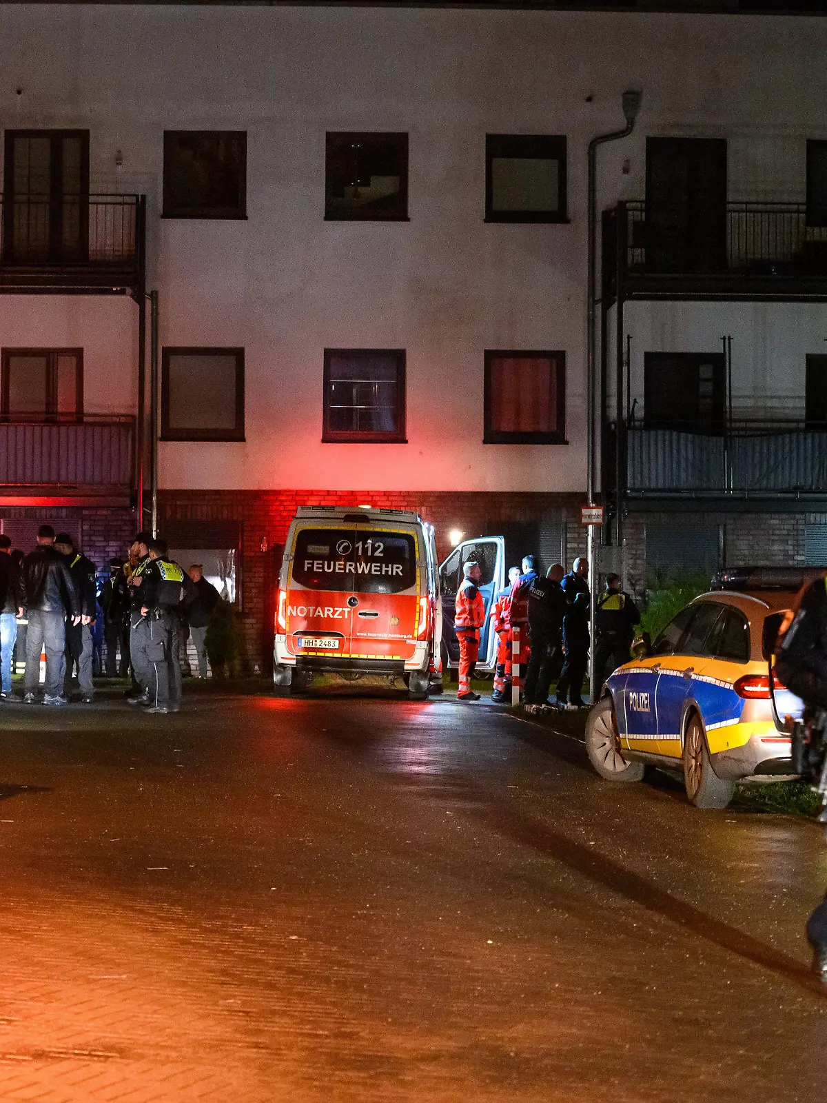 26.03.2023, Hamburg: Polizisten, Ermittler und Rettungskräfte stehen am abgesperrten Tatort.  Zwei Männer sind am späten Samstagabend in Hamburg-Langenhorn durch Schüsse ums Leben gekommen. Laut Angaben der Staatsanwaltschaft Hamburg von Sonntag handelt es sich bei einem der Toten um den mutmaßlichen Schützen. Der Mann soll nach dem derzeitigen Stand der Ermittlungen den anderen Mann mit mehreren Schüssen getötet haben. Foto: Jonas Walzberg/dpa +++ dpa-Bildfunk +++