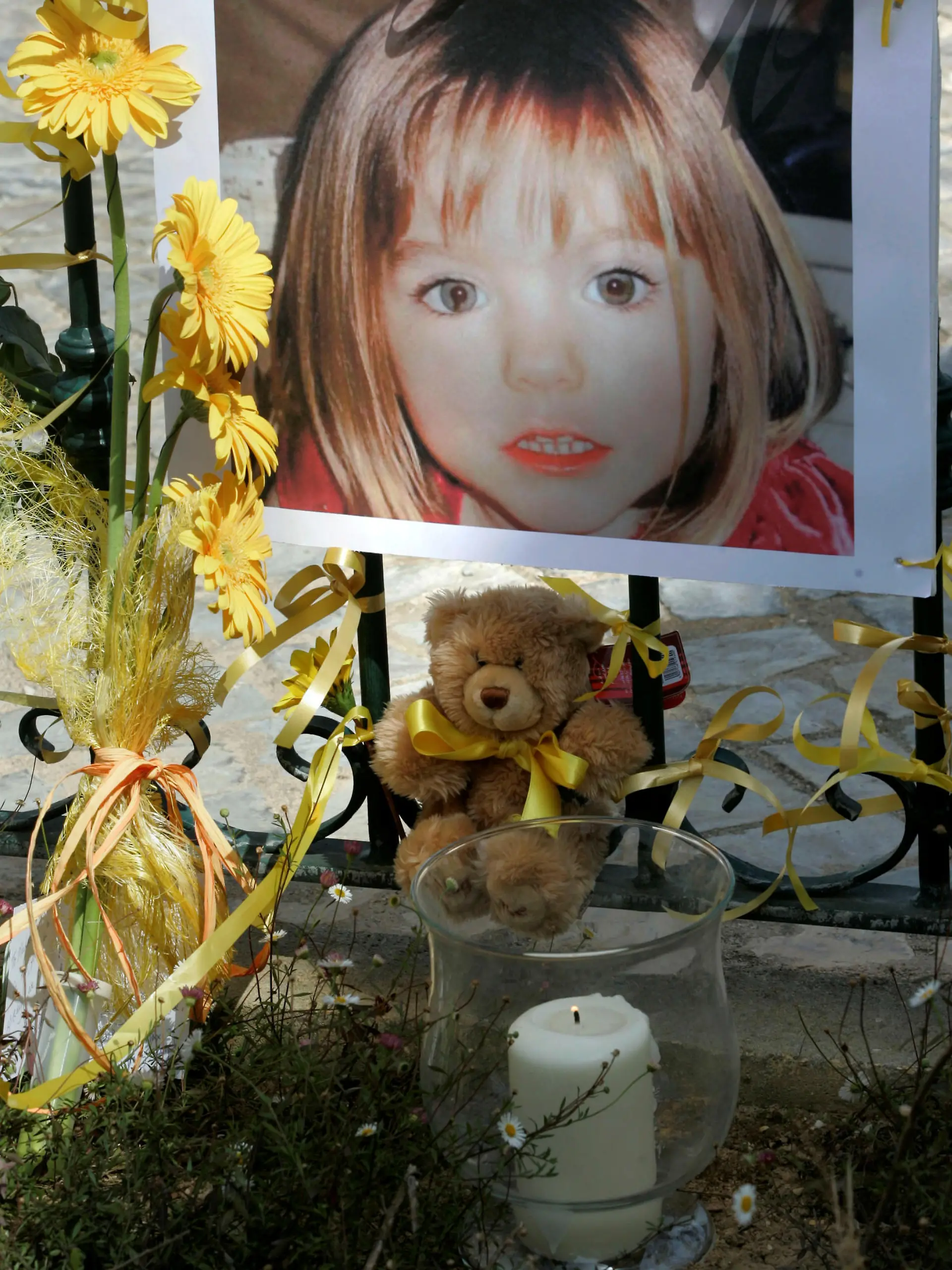 FILE PHOTO: Poster of the missing three-year-old British girl Madeleine McCann is surrounded by flowers and hope-bows in the Portuguese beach resort of Lagos May 12, 2007. REUTERS/Hugo Correia/File Photo