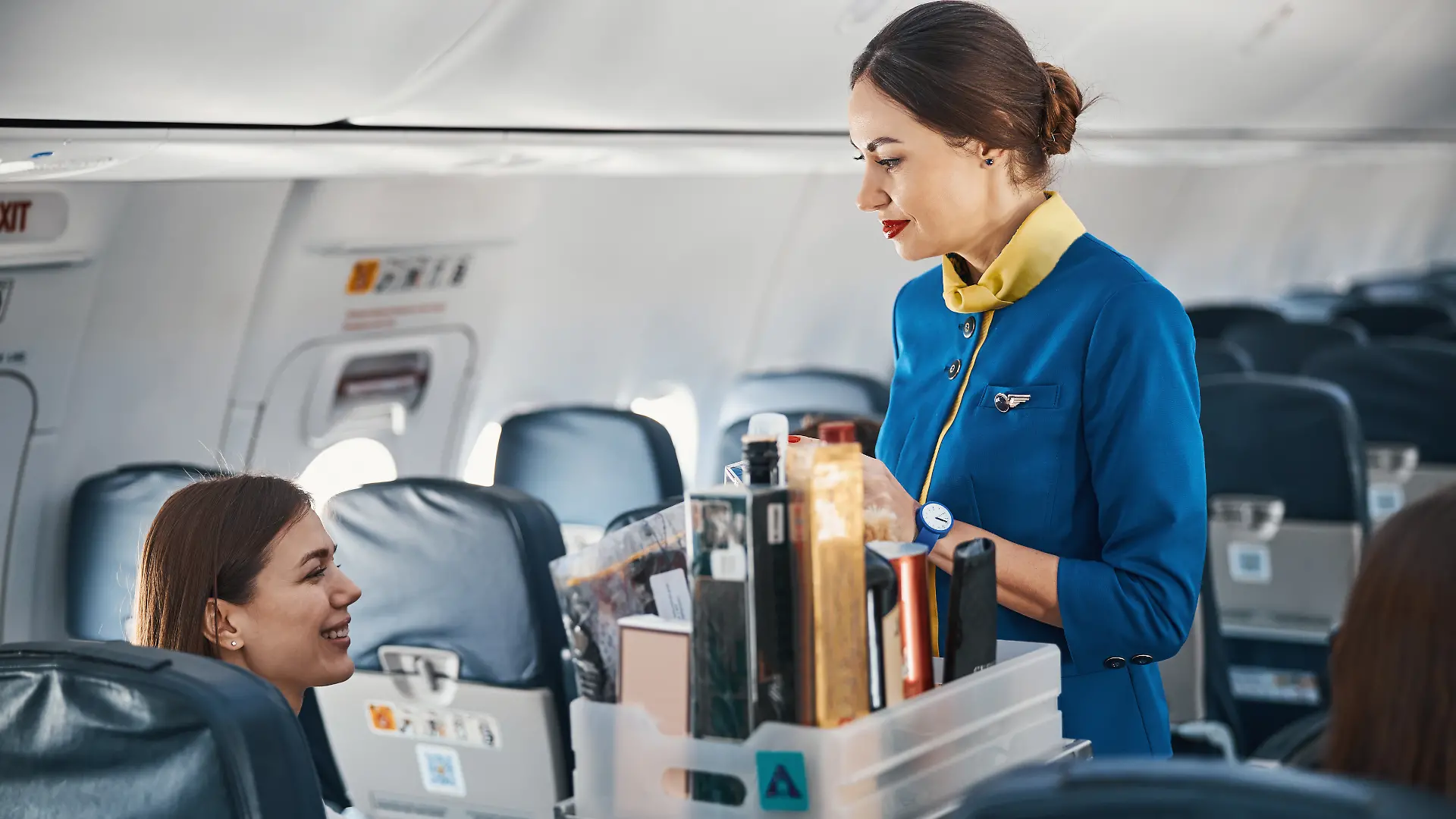 Flugbegleiterin verkauft Parfum im Flugzeug.