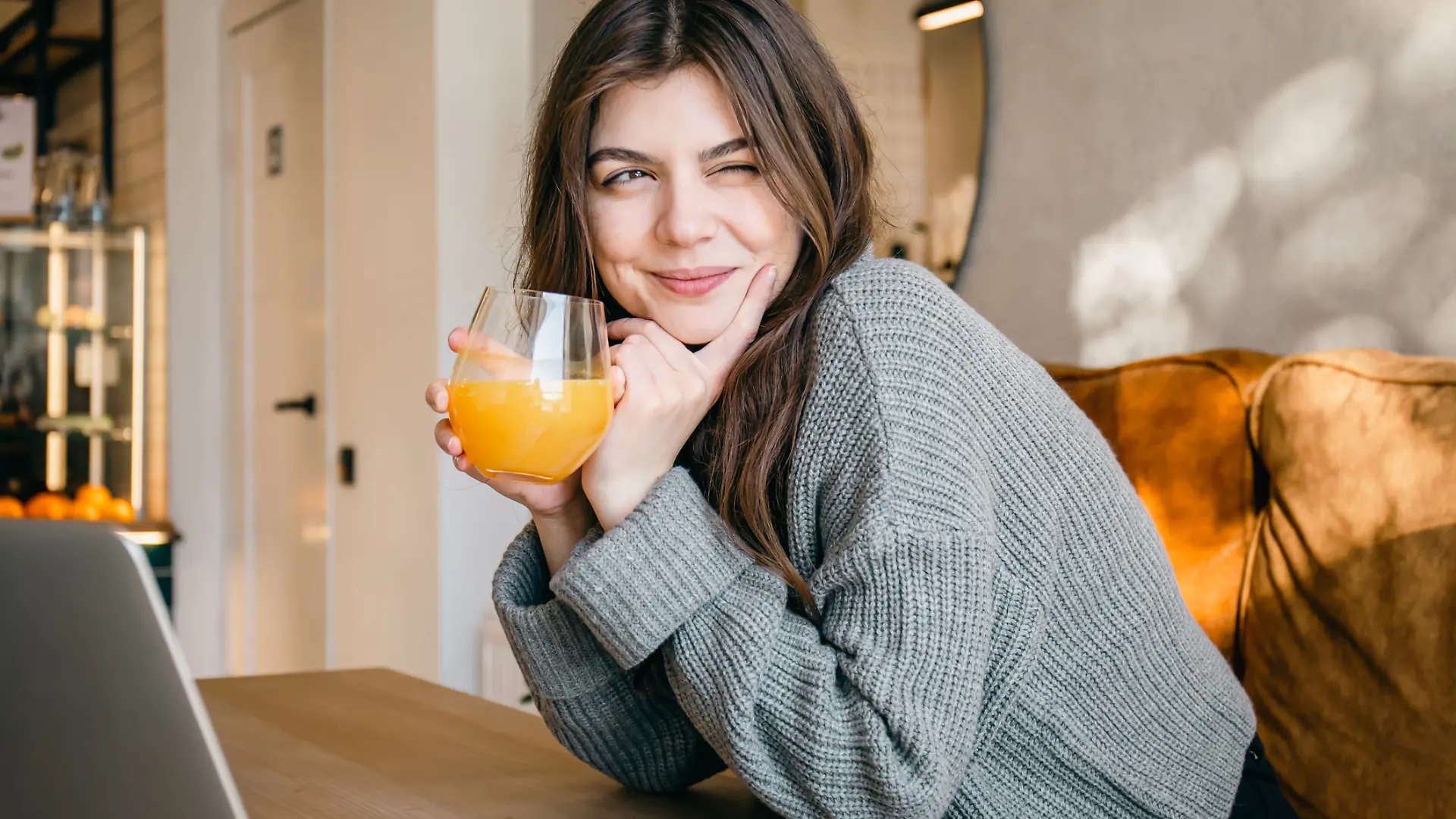 Eine glückliche junge Frau trinkt ein Glas Orangensaft.
