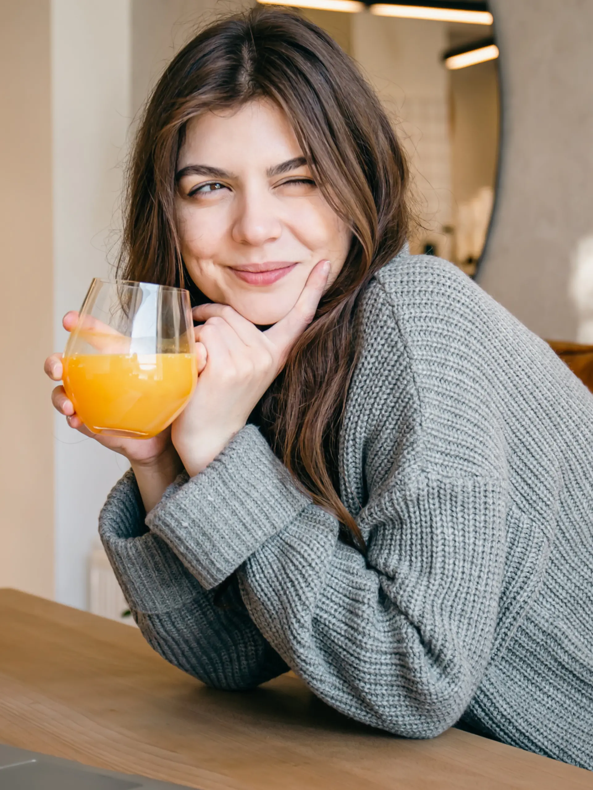 Eine glückliche junge Frau trinkt ein Glas Orangensaft.