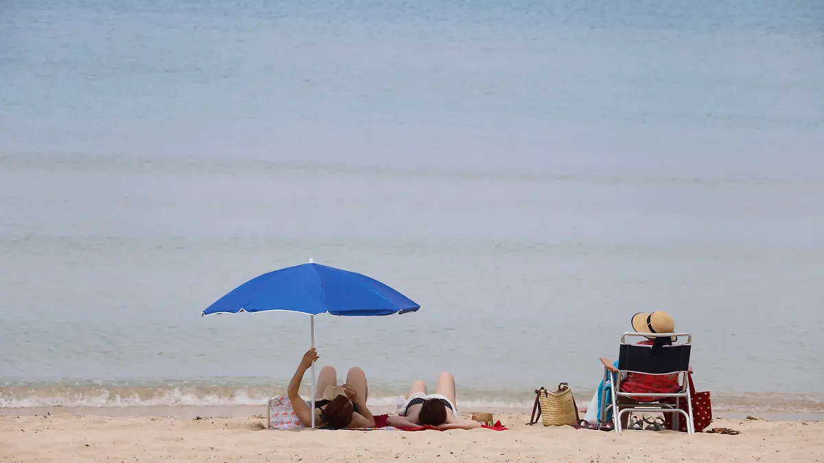 ARCHIV - 25.05.2020, Spanien, Palma de Mallorca: Menschen sonnen sich am Strand von Arenal. Mit großem Optimismus aber auch einem flauen Gefühl im Magen bereiten sich die Spanier auf die Wiedereröffnung des Landes für den Massentourismus am 1. Juli vor. (zu dpa "Spanien-Urlaub 2020: Sommer, Sonne, Strand und Schutzmaske") Foto: Clara Margais/dpa +++ dpa-Bildfunk +++