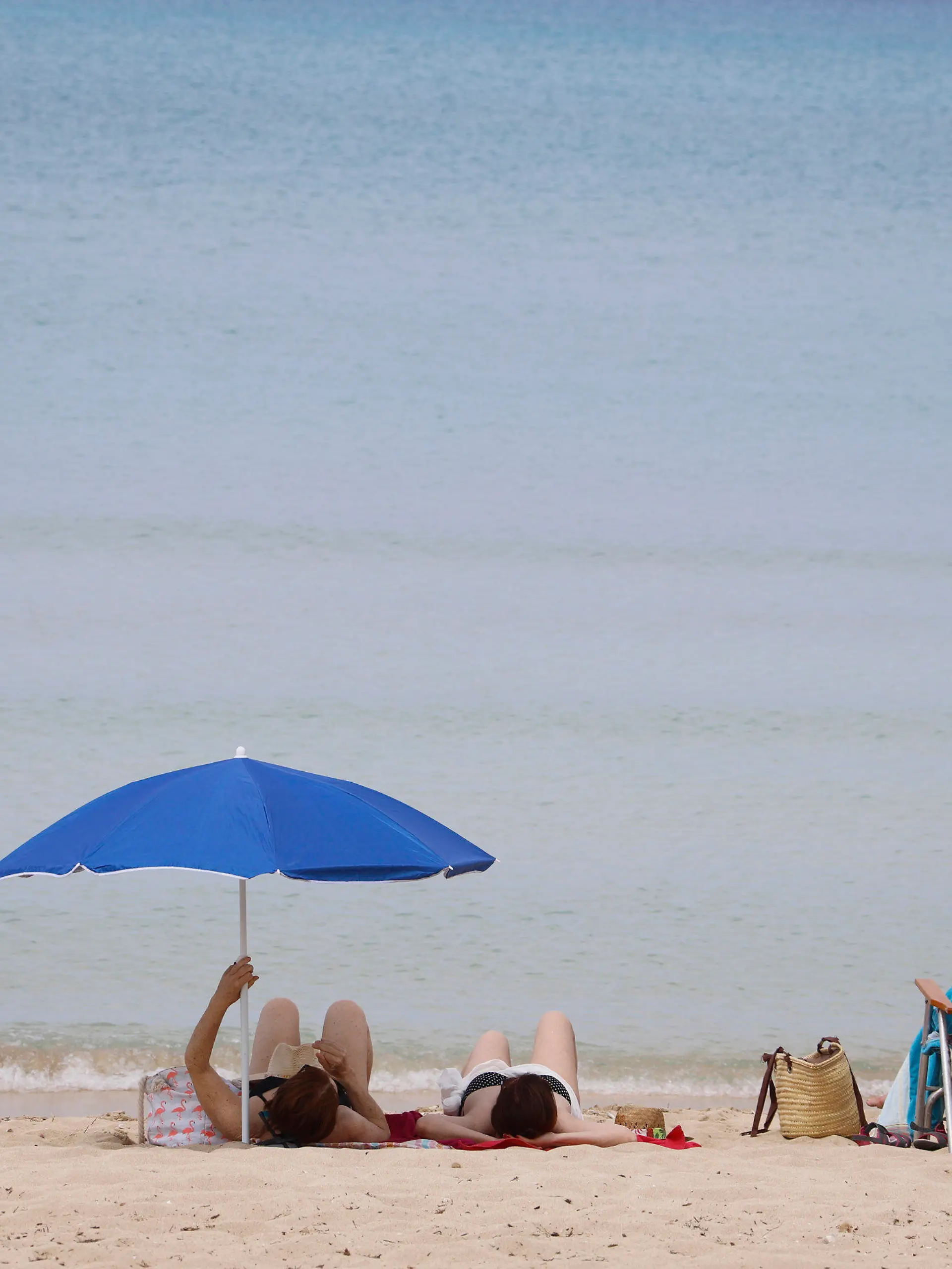 ARCHIV - 25.05.2020, Spanien, Palma de Mallorca: Menschen sonnen sich am Strand von Arenal. Mit großem Optimismus aber auch einem flauen Gefühl im Magen bereiten sich die Spanier auf die Wiedereröffnung des Landes für den Massentourismus am 1. Juli vor. (zu dpa "Spanien-Urlaub 2020: Sommer, Sonne, Strand und Schutzmaske") Foto: Clara Margais/dpa +++ dpa-Bildfunk +++