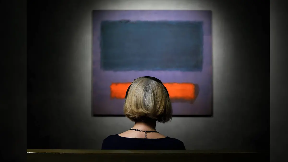 Frau sitzt vor dem Gemälde „Grey, Orange on Maroon, No. 8”