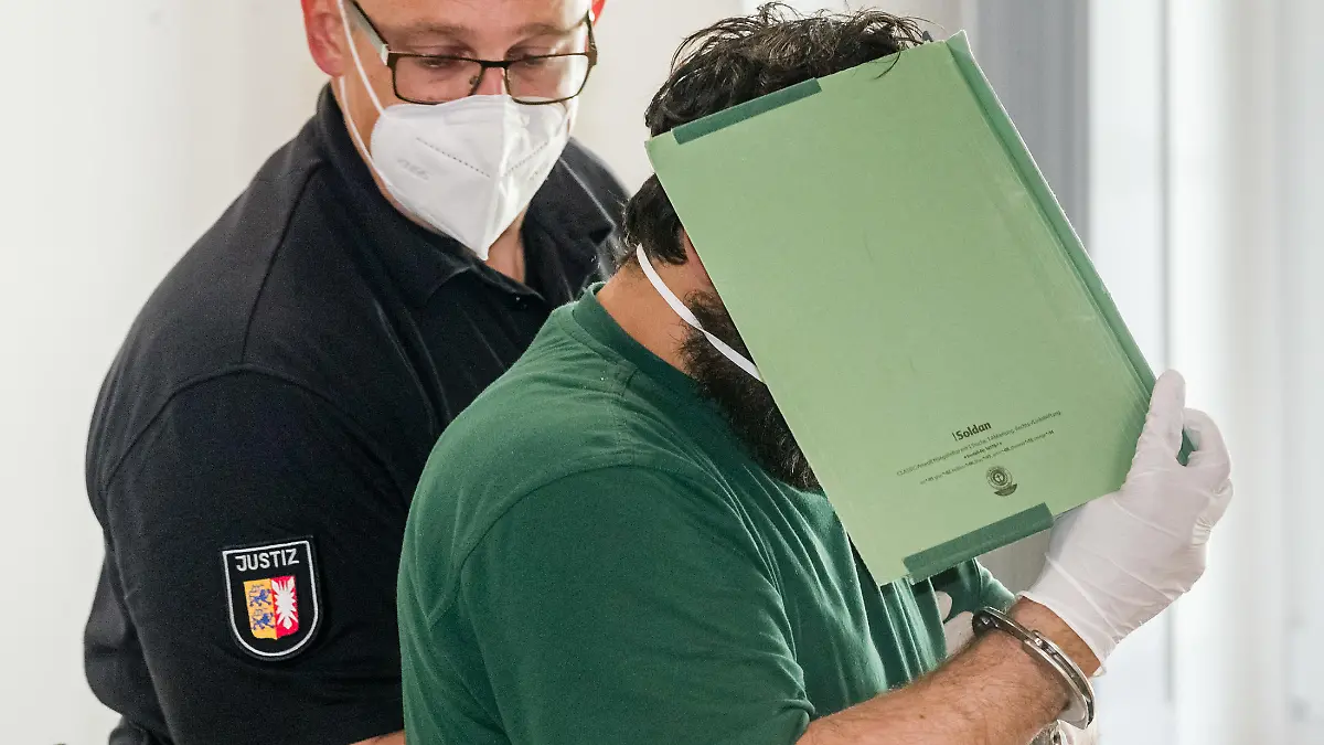 15.05.2020, Schleswig-Holstein, Lübeck: Der Angeklagte im Prozess um die Verschleppung und Vergewaltigung einer Studentin verbirgt im Gerichtssaal sein Gesicht hinter einem Aktendeckel. Er soll sein Opfer im Oktober 2019 entführt und nach der Tat auf einem einsamen Feldweg ausgesetzt haben. Er muss sich wegen versuchten Mordes, Vergewaltigung und Freiheitsberaubung vor dem Landgericht Lübeck verantworten. Foto: Markus Scholz/dpa +++ dpa-Bildfunk +++