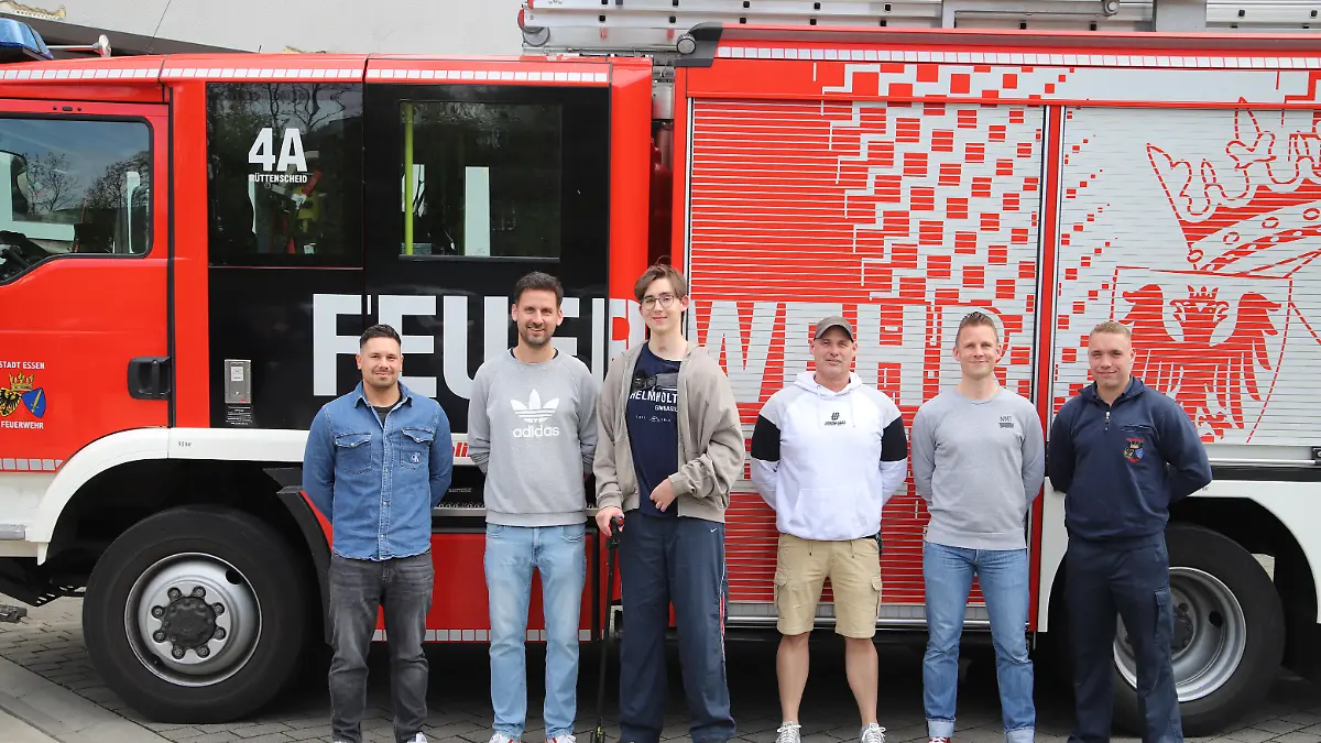 Keanu Fredriksson (3.vl) steht mit Einsatzkräften der Feuerwehr, die bei seinem Unfall im Einsatz waren, vor einem Löschfahrzeug. Rund anderthalb Jahre nach einem dramatischen Unfall hat ein damals 17-jähriger Schüler aus Essen seinen Lebensrettern bei der Feuerwehr in Essen gedankt.