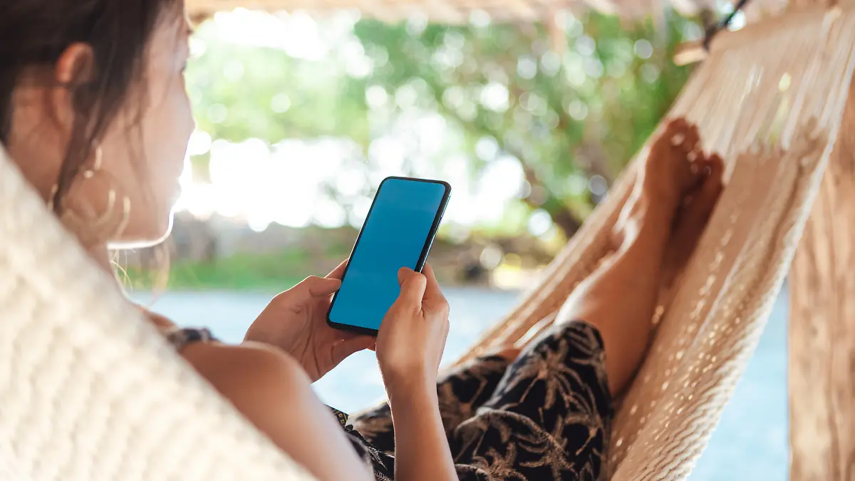Frau in Hängematte mit Handy.