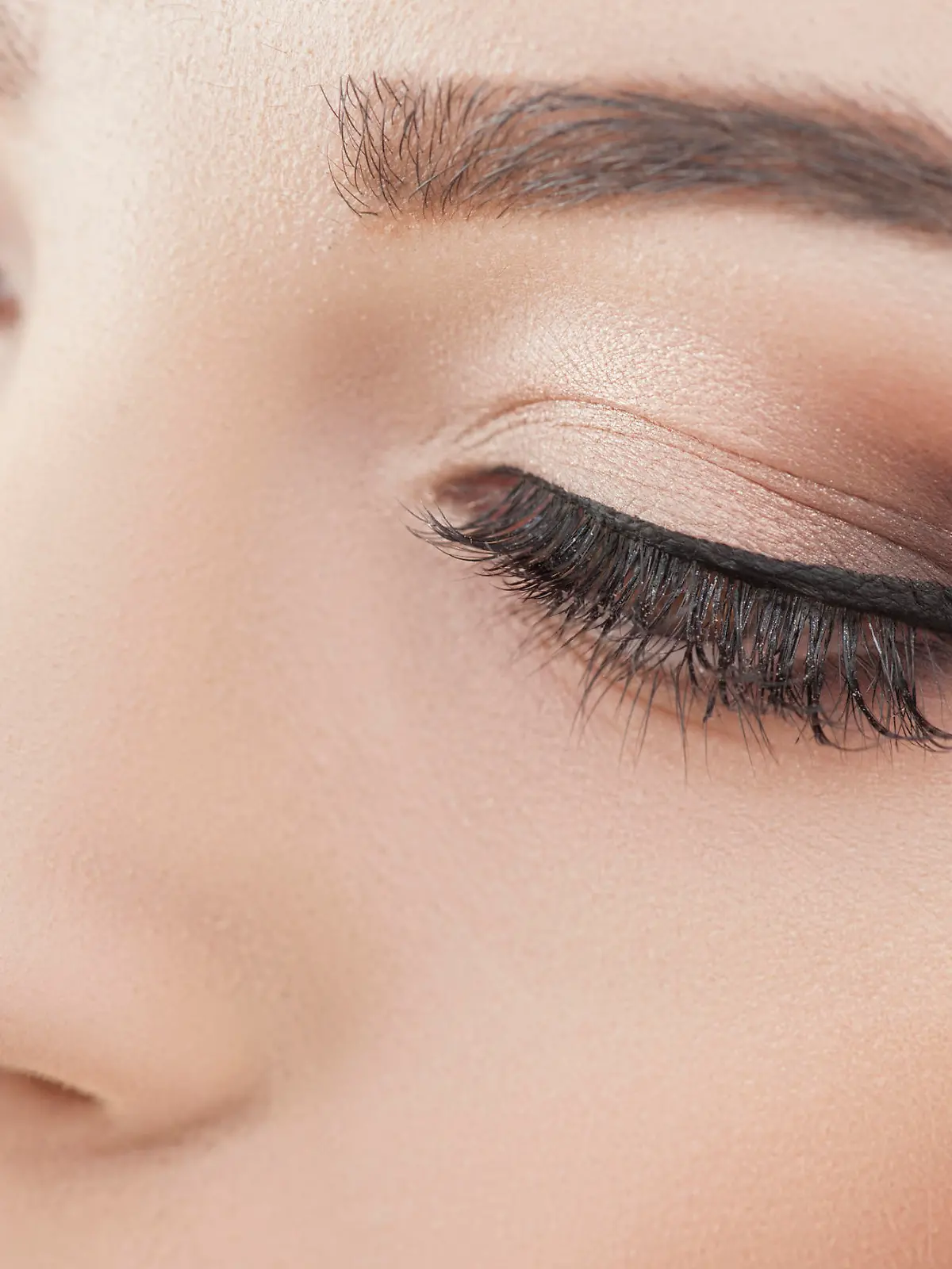 Close up of female eyes. The young woman is applying the eyeliner on her eye