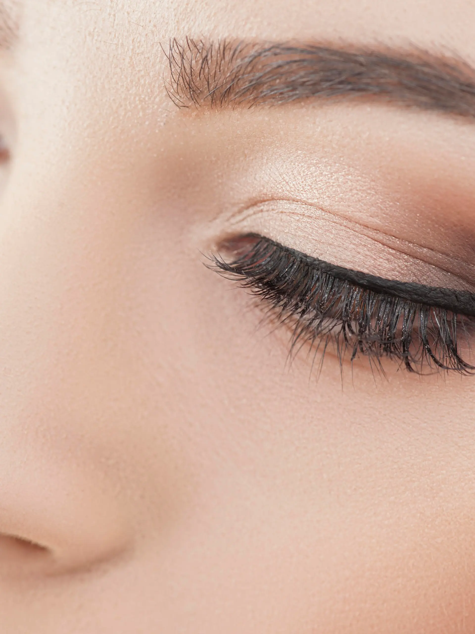 Close up of female eyes. The young woman is applying the eyeliner on her eye