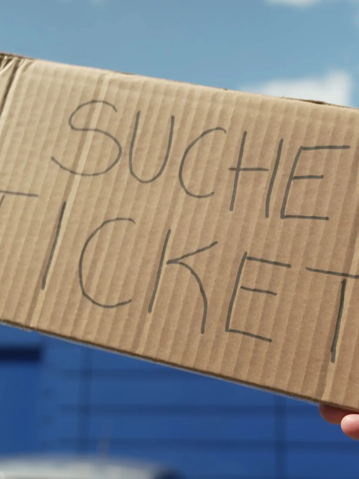 Eine Hand hält ein Pappschild mit der Aufschrift „Suche Ticket”