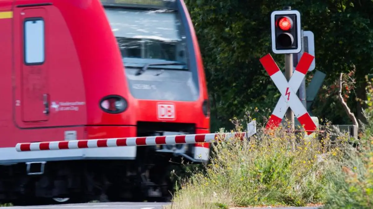 S-Bahn der Deutschen Bahn (DB) fährt an einem Bahnübergang mit einer roten Ampel vorbei