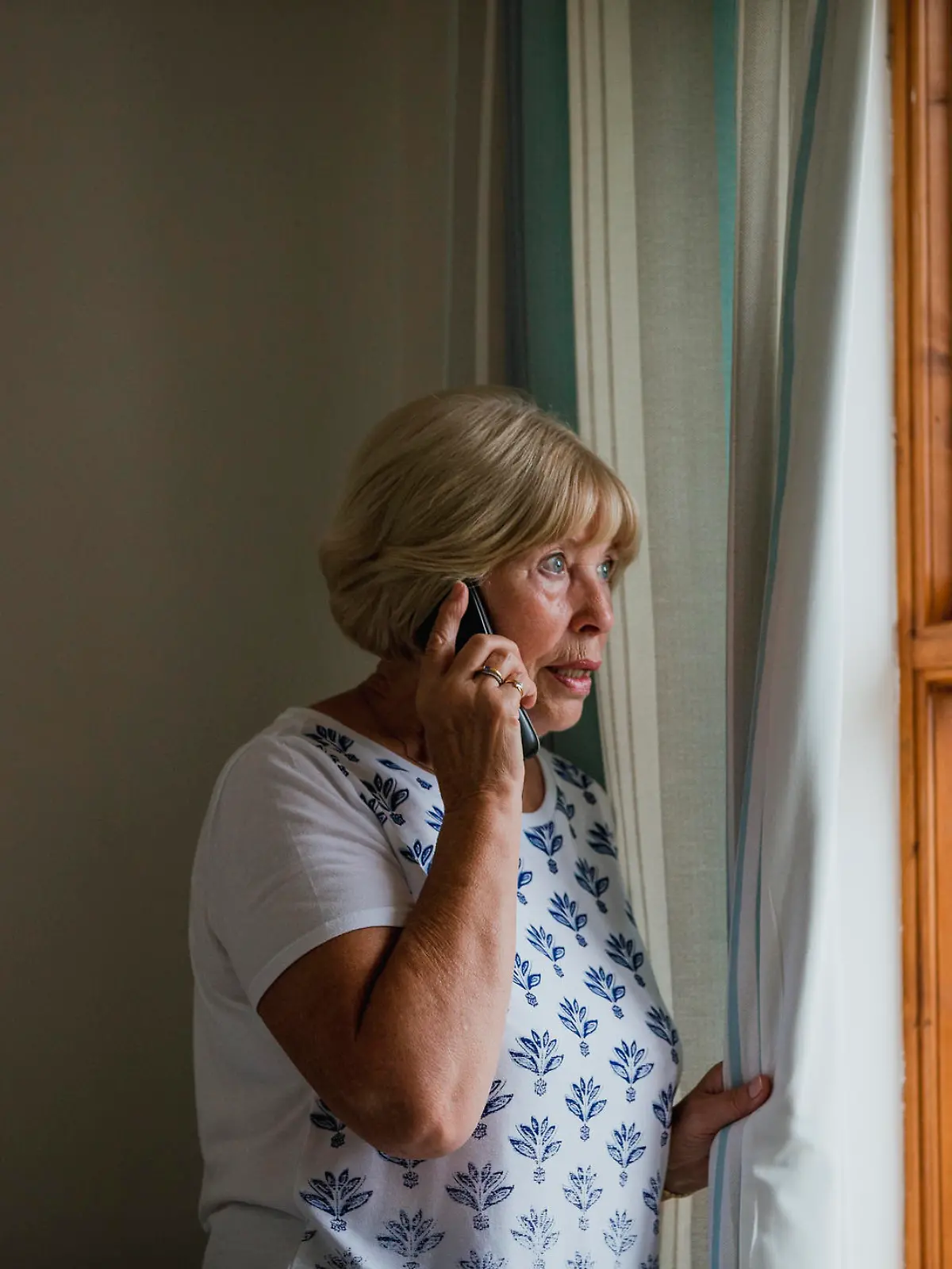 Alte Frau am Telefon schaut aus dem Fenster
