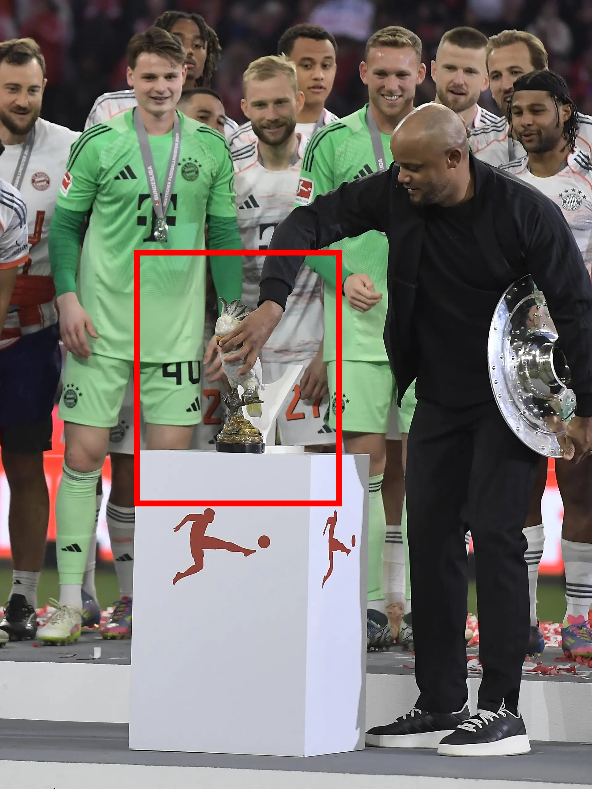 Vincent Kompany platziert einen silbernen Kakadu auf dem Sockel.